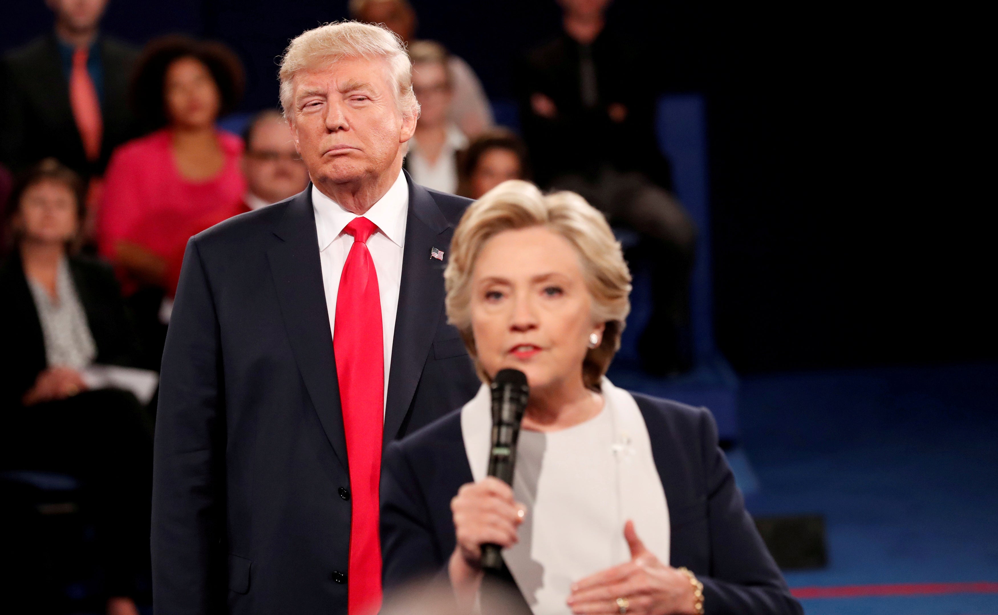 Donald Trump looms over Hillary Clinton as she answers a question from the audience during their presidential town hall debate at Washington University in St. Louis, Missouri, U.S., October 9, 2016.