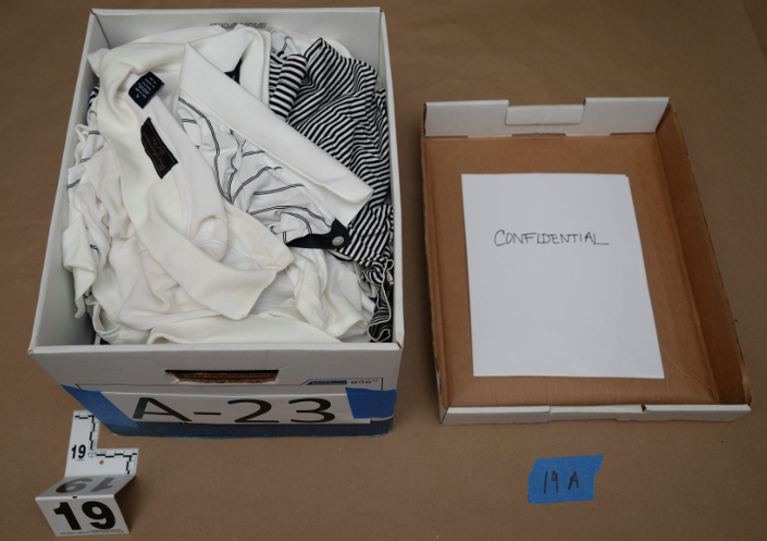 Golf shirts are stuffed in a box with a paper reading ‘confidential.’