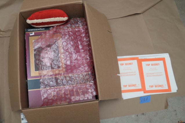 Documents marked ‘top secret’ appear next to boxes with bubble wrap and other knicknacks.
