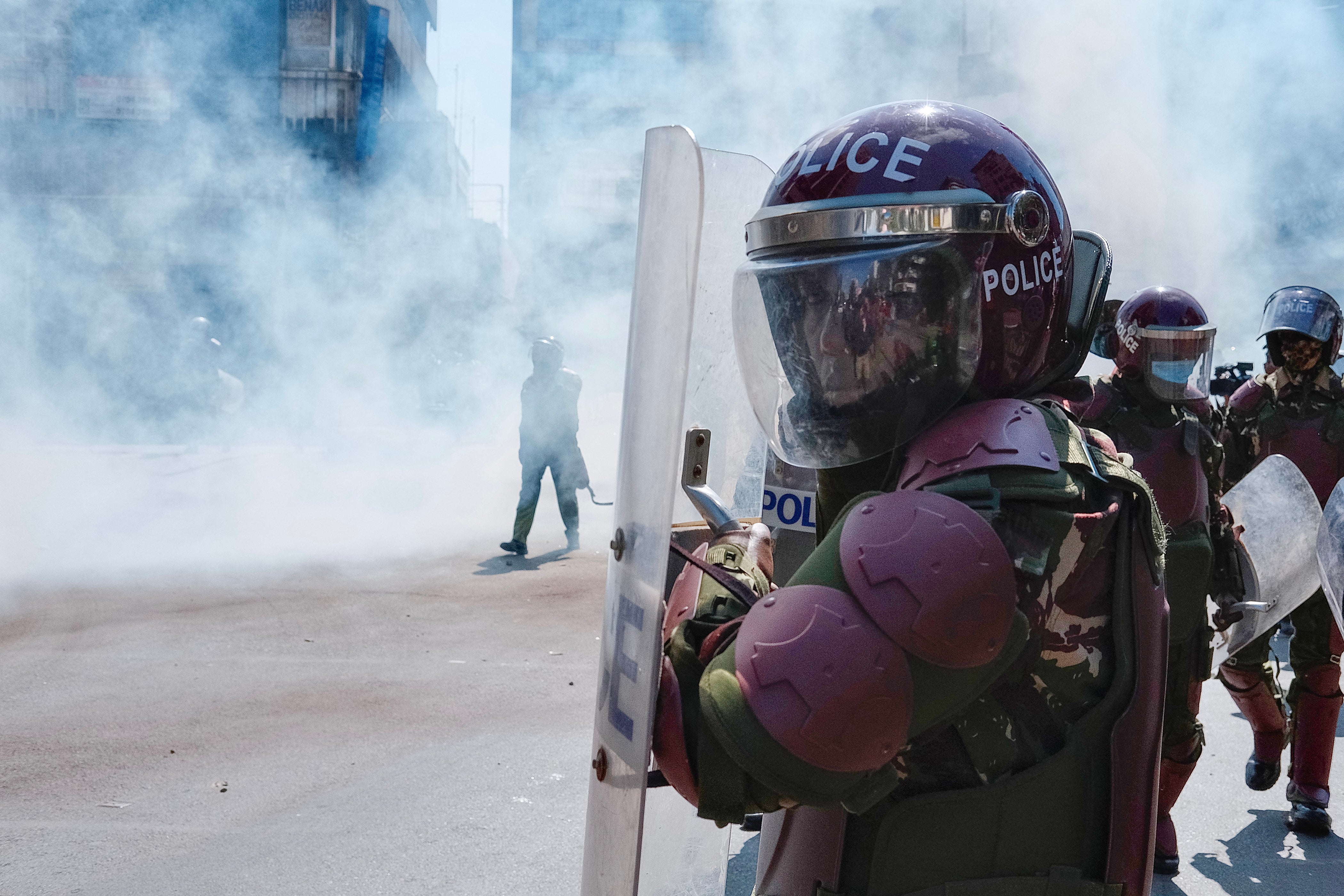 A member of the Kenyan security forces looks on from his helmet as he is deployed amid tear gas during a nationwide strike to protest against tax hikes