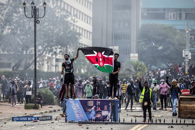 <p>Protesters hold a Kenyan flag outside the Kenyan Parliament after storming the building during a nationwide protest against a tax bill</p>