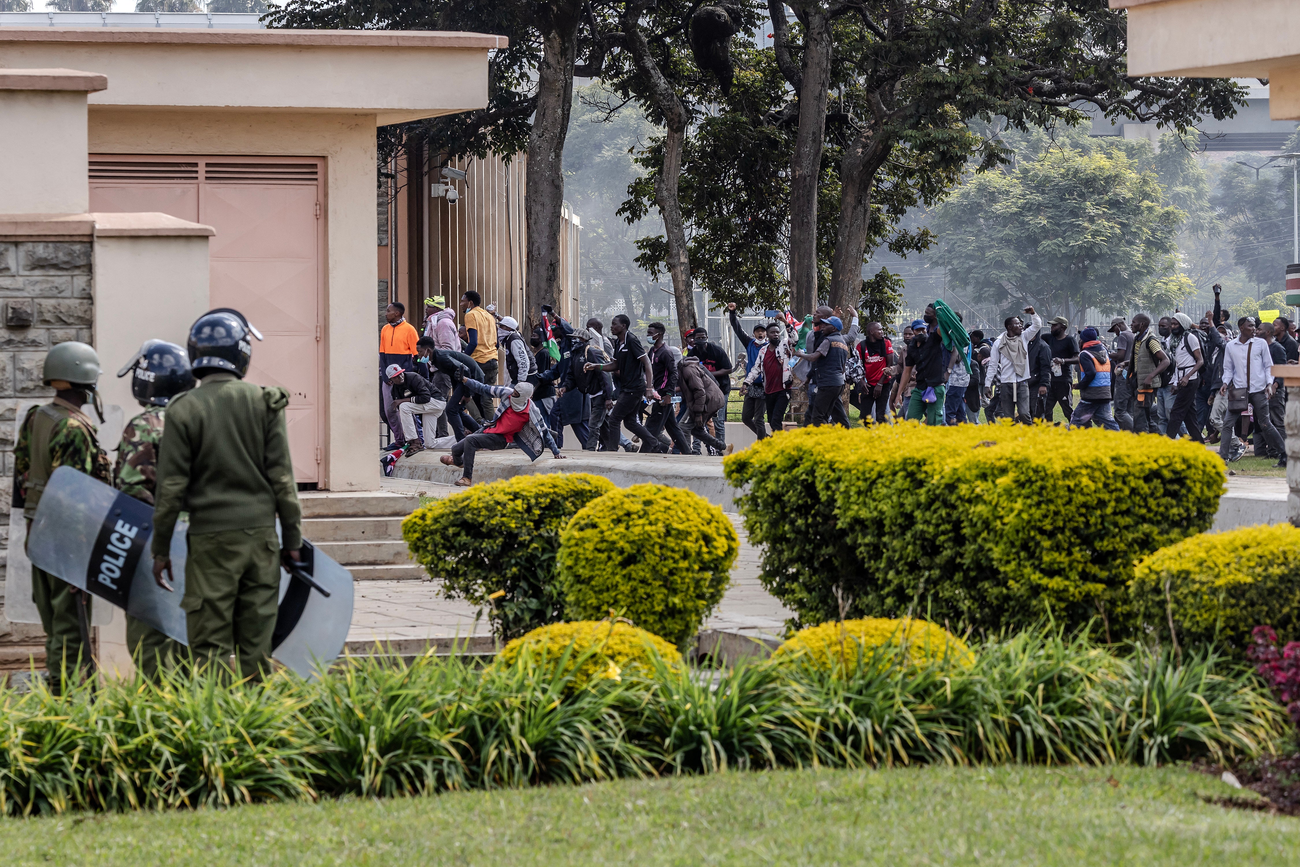 Protesters run inside the Kenyan parliament as police look on