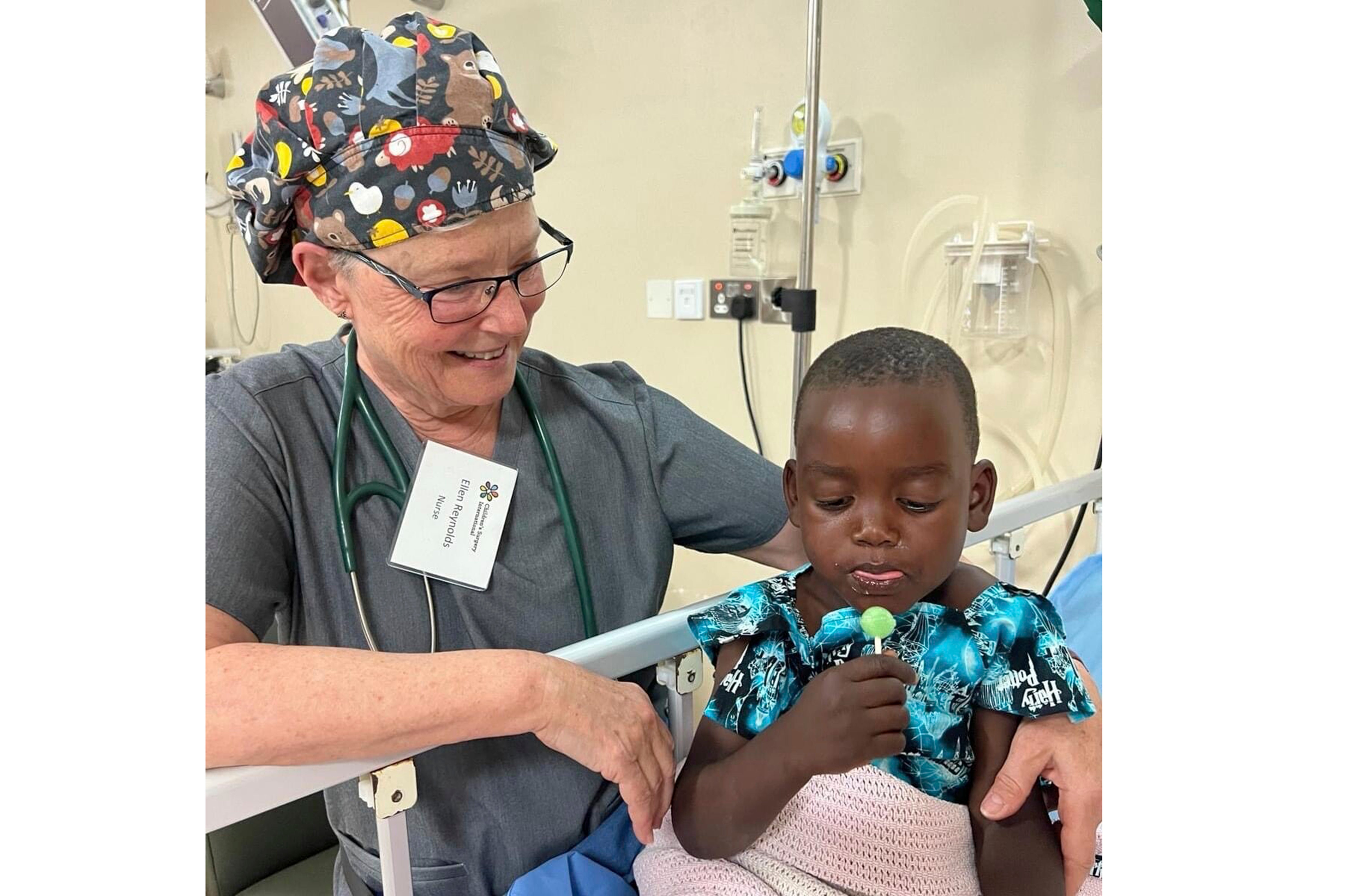 Nurse Ellen Reynolds of Children’s Surgery International gives a lollipop to patient Ategeka, whose last name they are keeping confidential to protect his privacy, in a bed at Holy Innocents Children's Hospital in Mbarara, Uganda on Feb. 2, 2024. Ategeka is wearing a Harry Potter-themed gown made by Giuliana Demma