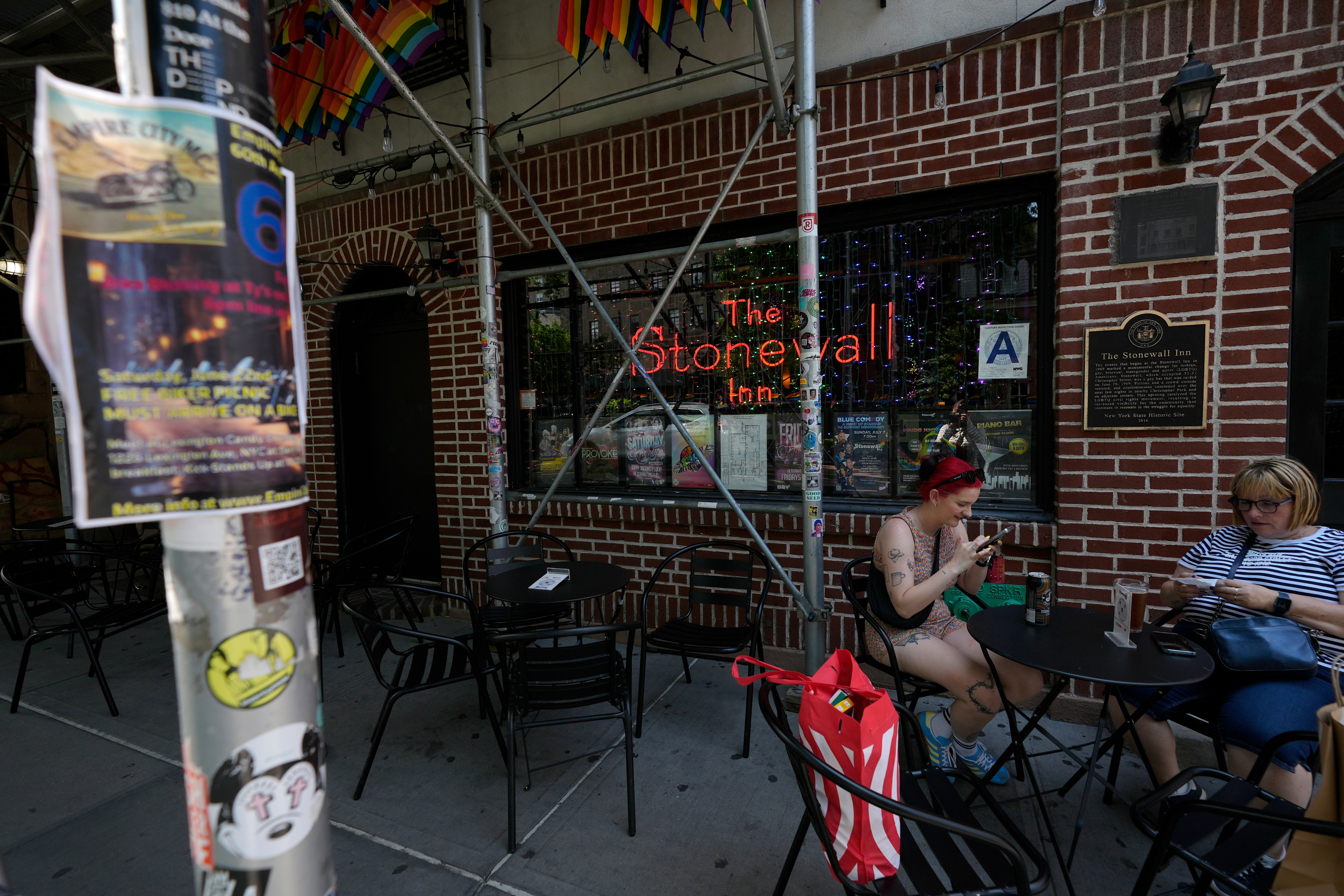 People sit outside the Stonewall Inn, Monday, June 17, 2024, in New York. The community is reclaiming the building and its place in history as it opens it as the Stonewall National Monument's visitor center on Friday, June 28, the anniversary of the 1969 rebellion that helped reshape LGBTQ+ life in the United States in the ensuing decades