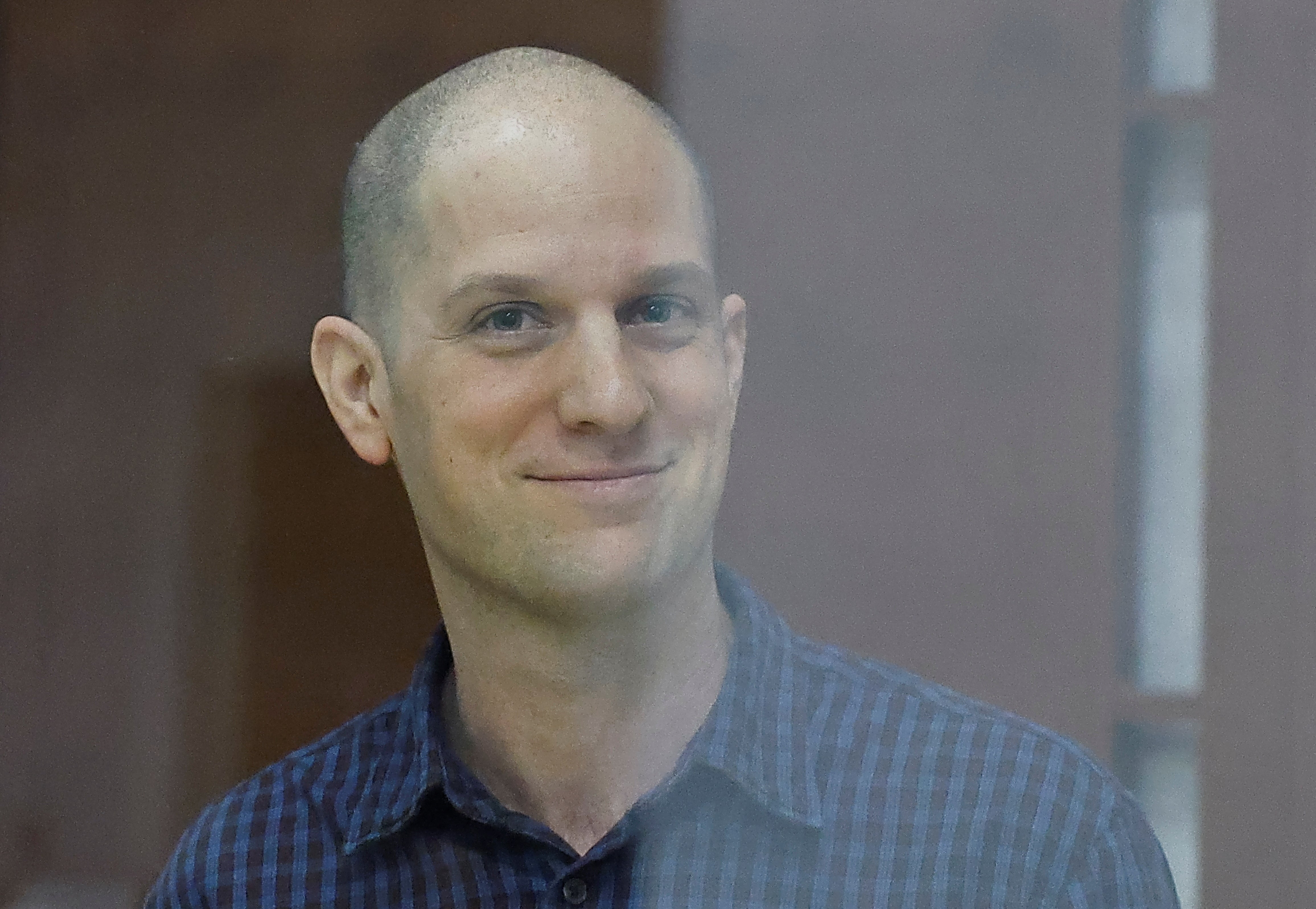 Wall Street Journal reporter Evan Gershkovich, who stands trial on spying charges, smiles inside an enclosure for defendants before a court hearing