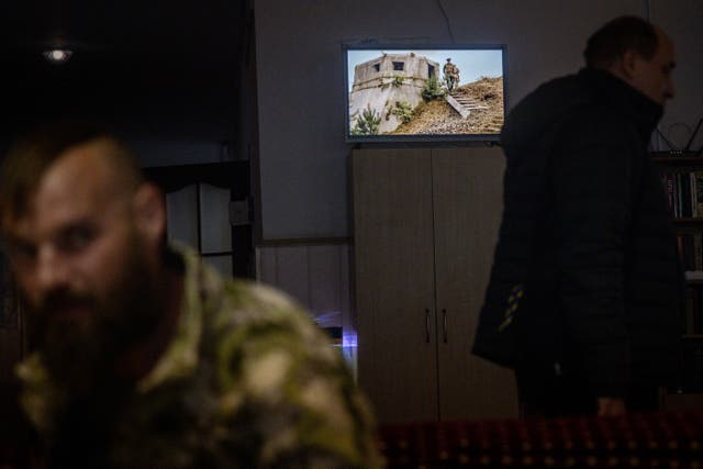 <p>A war movie plays on a television in the background as patients sit around at a psychiatric hospital in Kyiv</p>