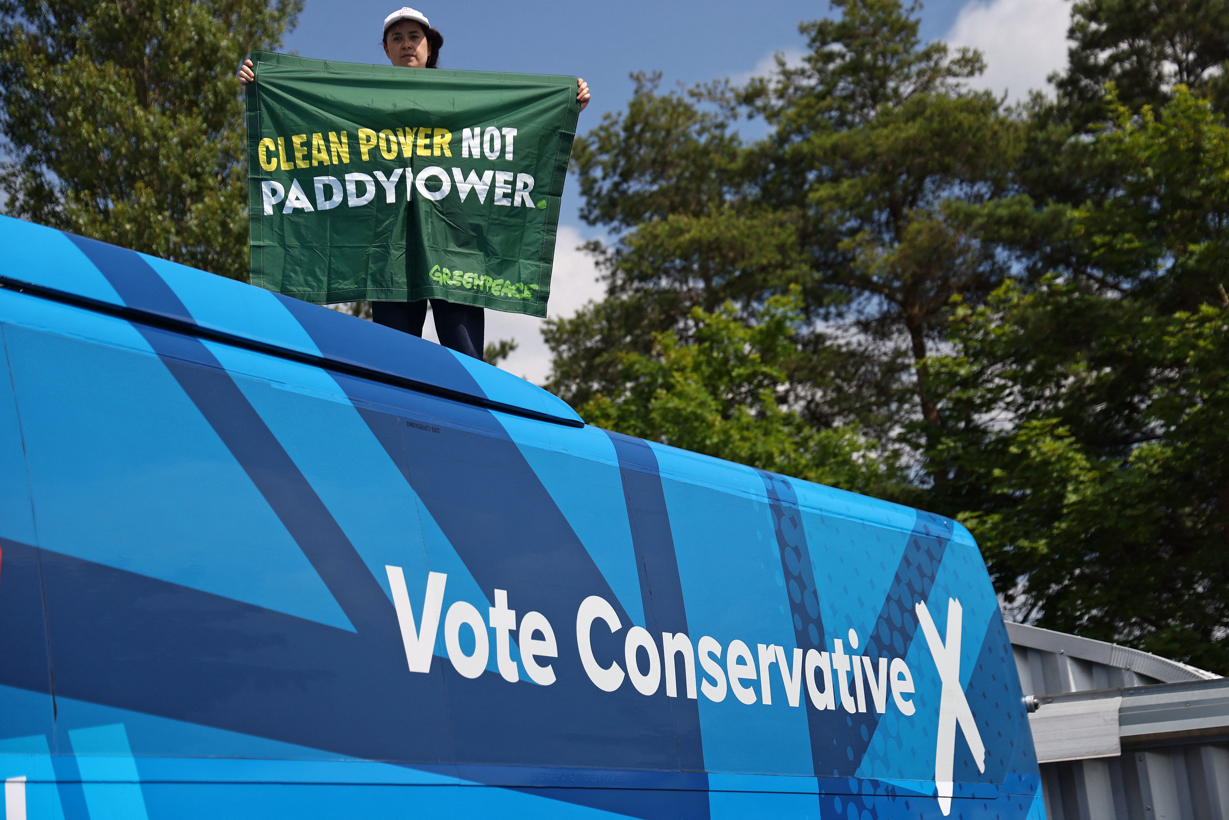 A demonstrator holds a Greenpeace banner calling for 'Clean Power, not PaddyPower' as they protest on the roof of the Conservative Party's General Election campaign bus in Nottingham