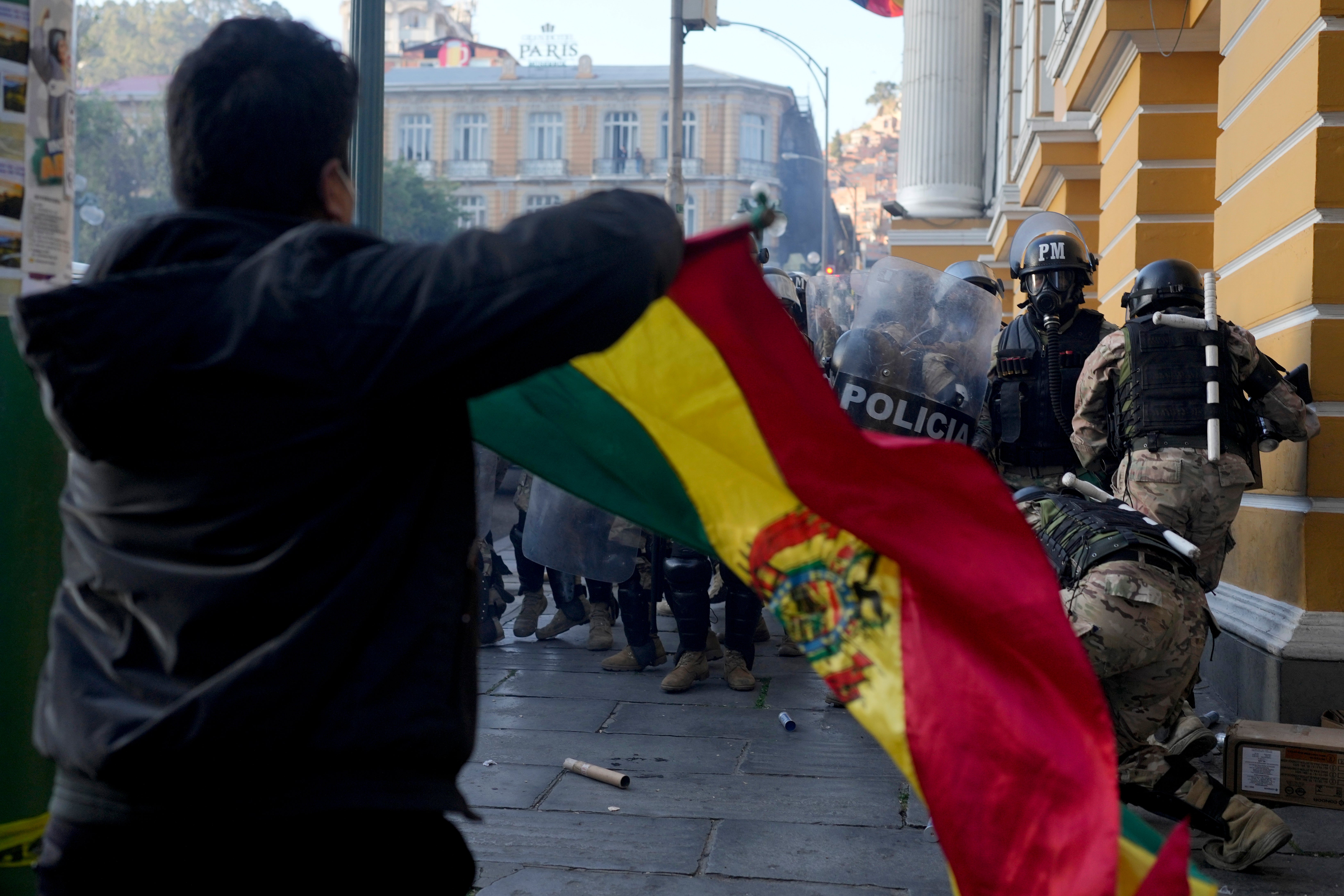 2024年6月26日水曜日、ボリビアのラパスで、クーデター未遂後にムリーリョ広場から逃げる兵士たちを横目に、ボリビアの国旗を振るルイス・アルセ大統領の支持者。
