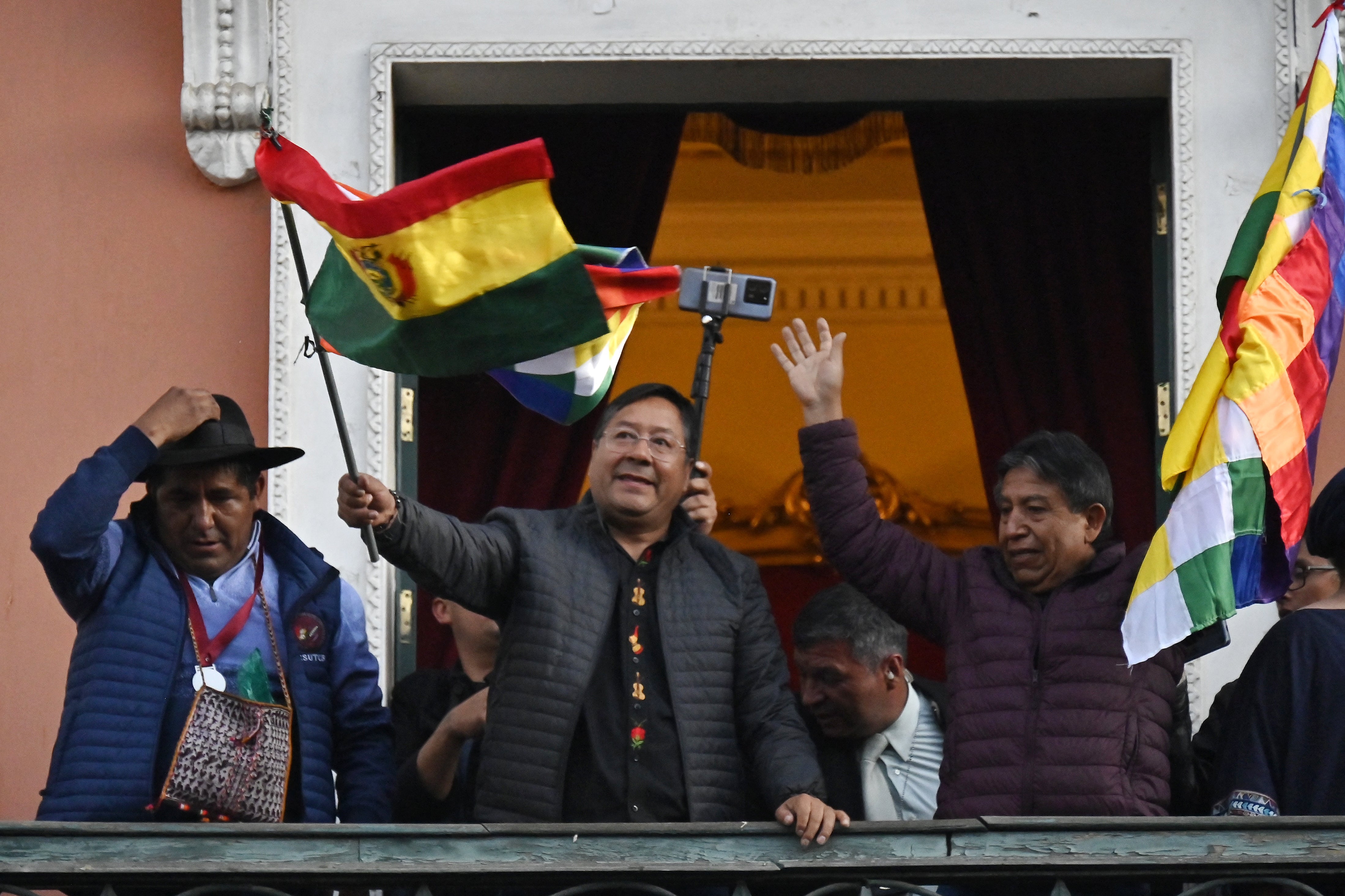 Bolivijský prezident Luis Arce mává bolivijskou vlajkou na balkoně vládního paláce v La Paz