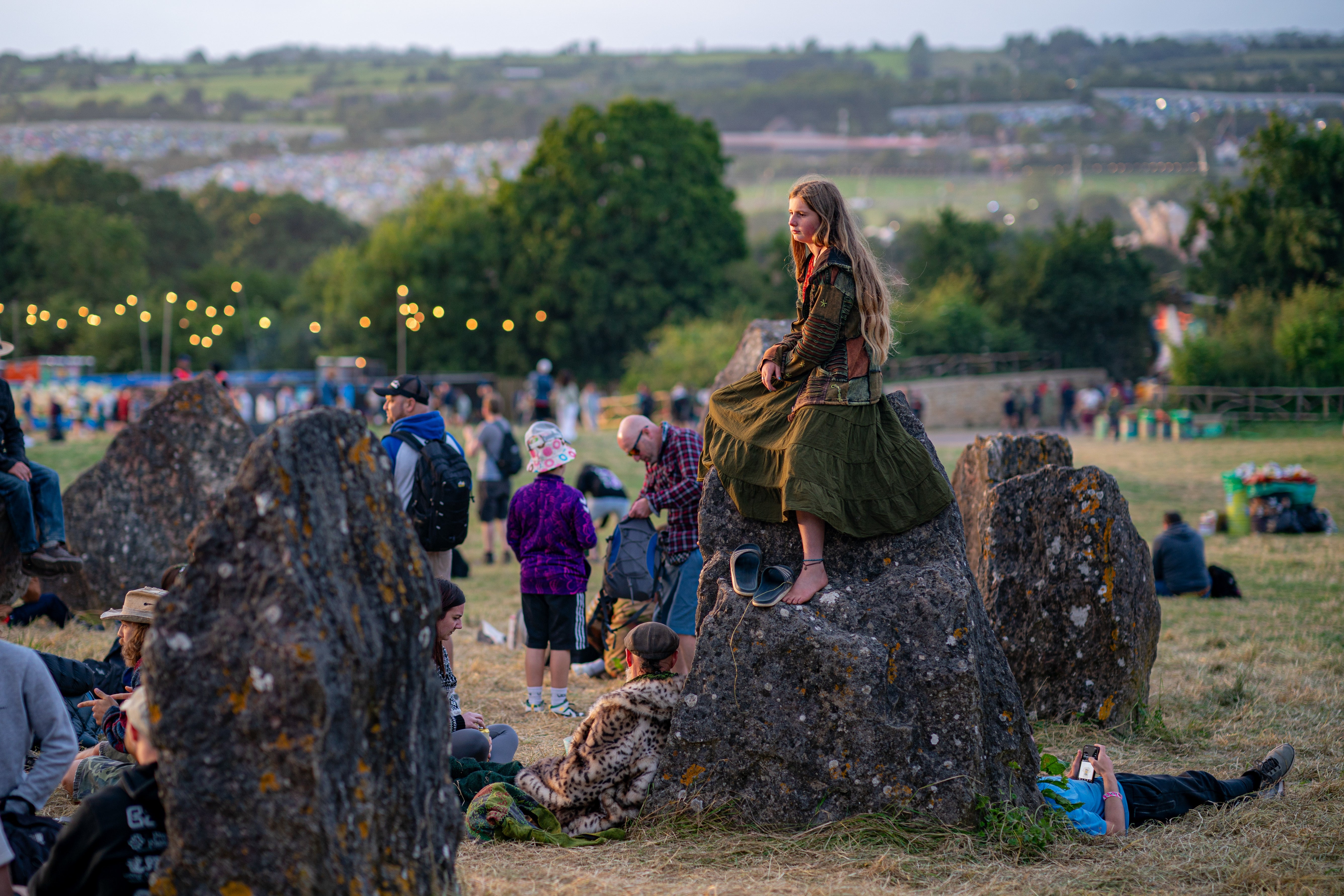 A person sits on the stone circle at the Glastonbury Festival (Ben Birchall/PA)