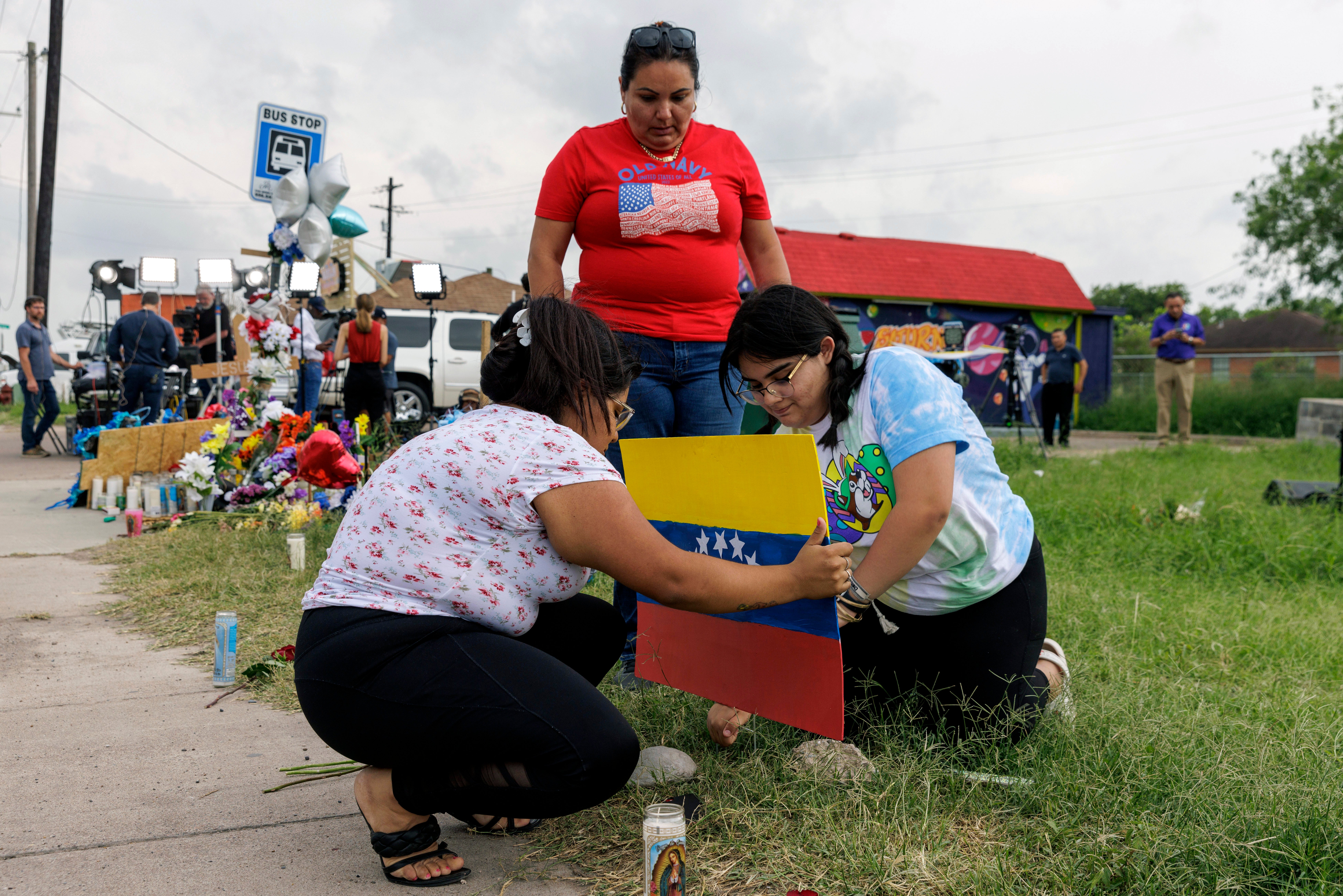 Patty Limon watches her daughters Annaalexis Limon and Monica Limon place a Venezuelan flag, painted by Annaalexis, at a memorial where eight migrants were killed, and several others injured the day before while waiting at a bus stop in Brownsville, Texas. The driver has now been found guilty.