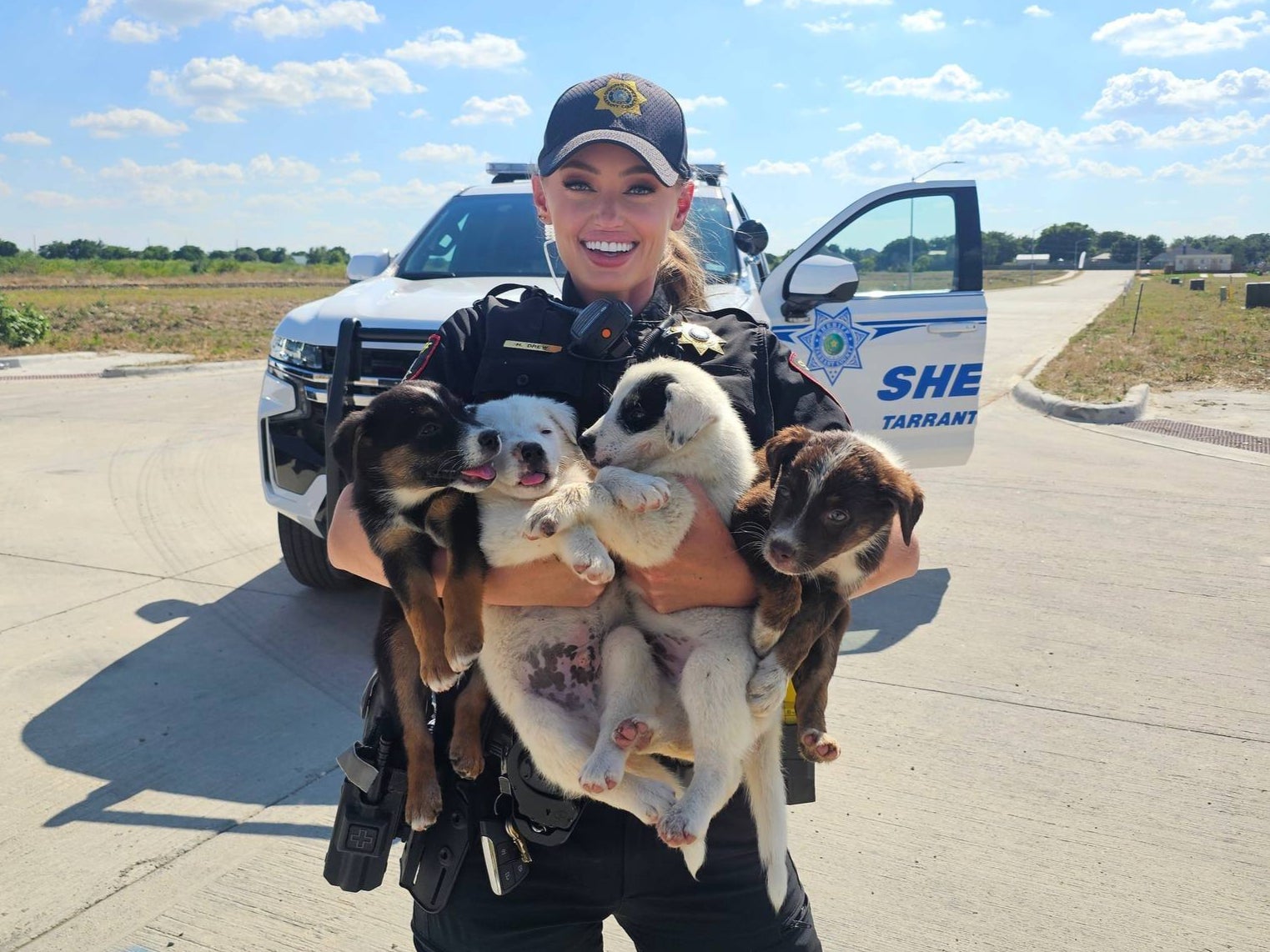 A member of the Tarrant County Sheriff’s Office pictured holding several puppies who were abandoned in a heat wave with no water. All eight puppies have since been adopted