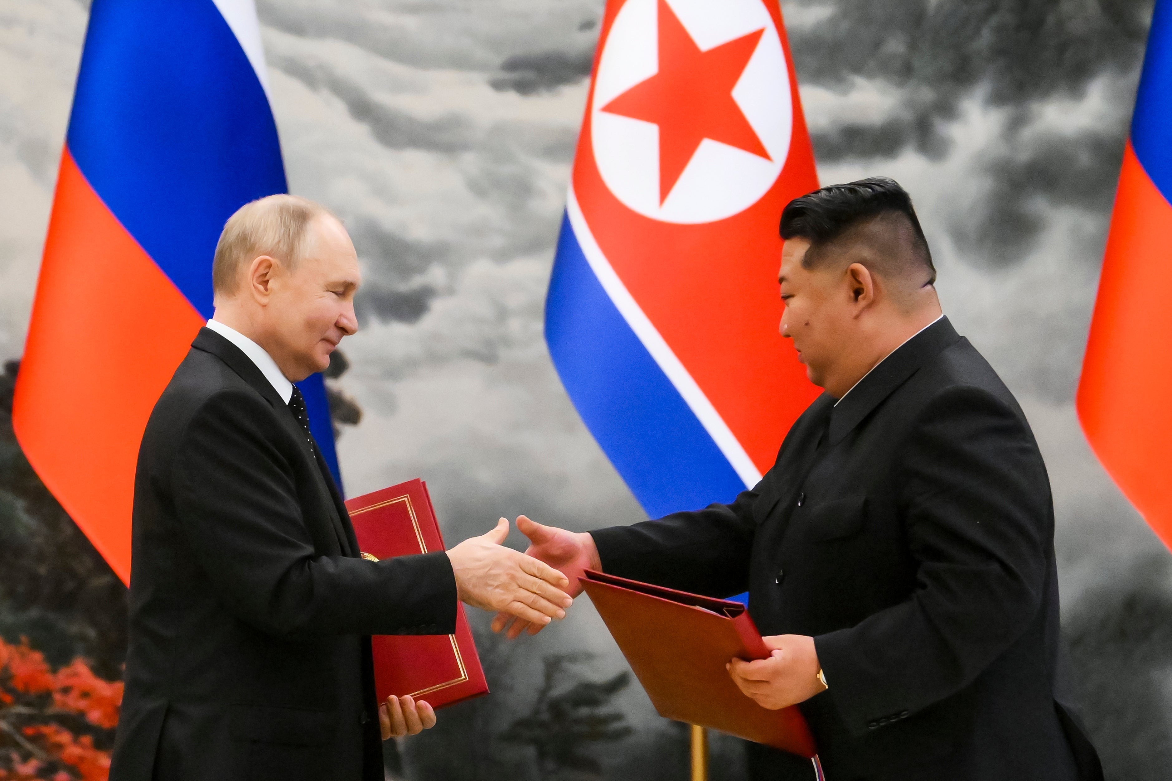 Russian President Vladimir Putin, left, and North Korean leader Kim Jong Un exchange documents during a ceremony