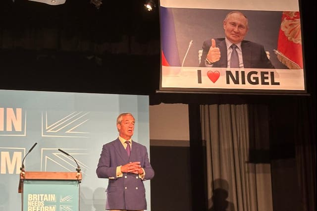 <p>Nigel Farage was speaking as a banner of Putin was lowered behind him </p>