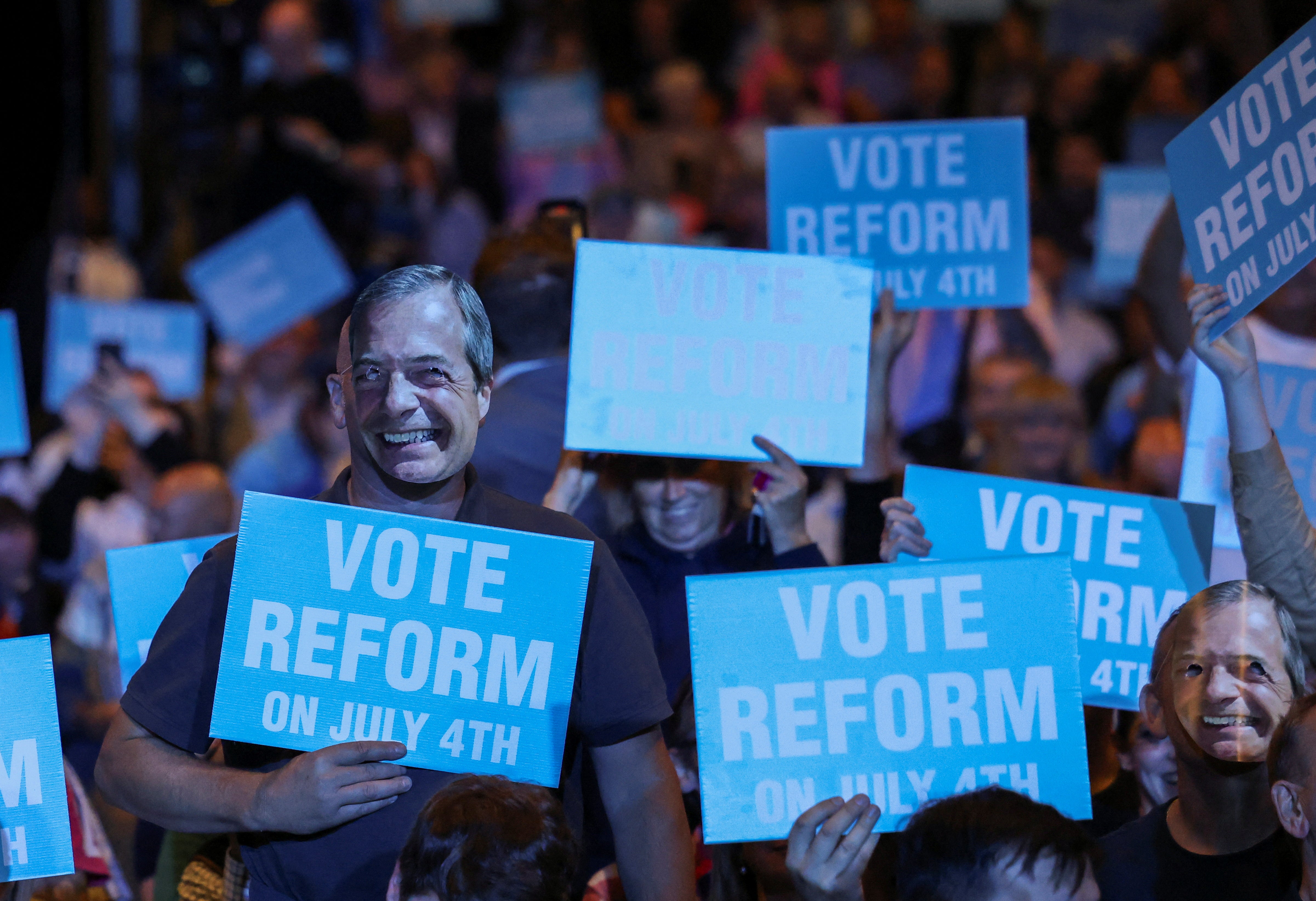 Ein Anhänger der britischen Reformpartei trägt während der Kundgebung der Partei am Sonntag in Birmingham eine Nigel-Farage-Maske