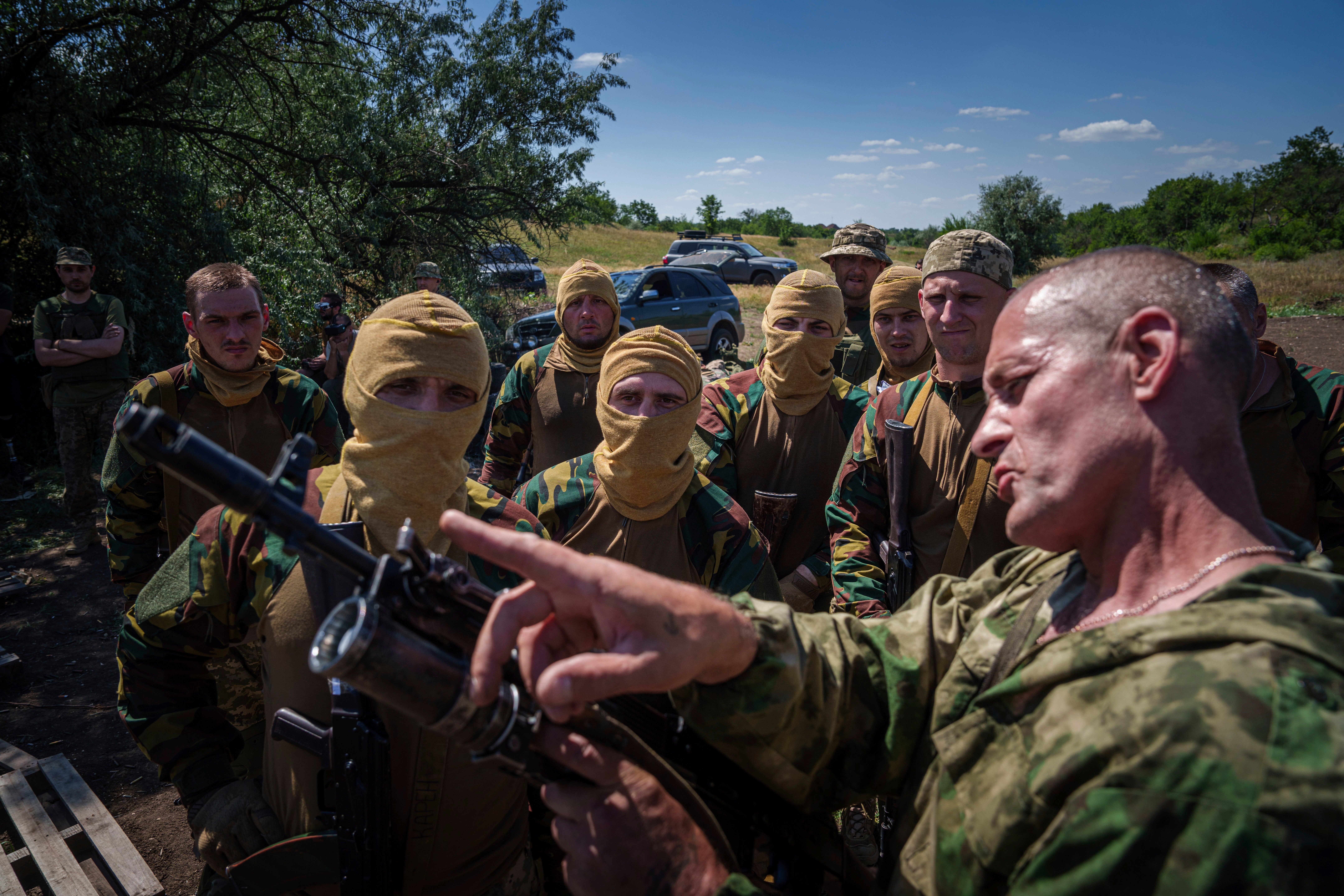 A Ukrainian military instructor of Arey Battalion demonstrates to convict prisoners who have joined the Ukrainian army how to use a grenade luncher on a rifle during training at the polygon, in the Dnipropetrovsk region