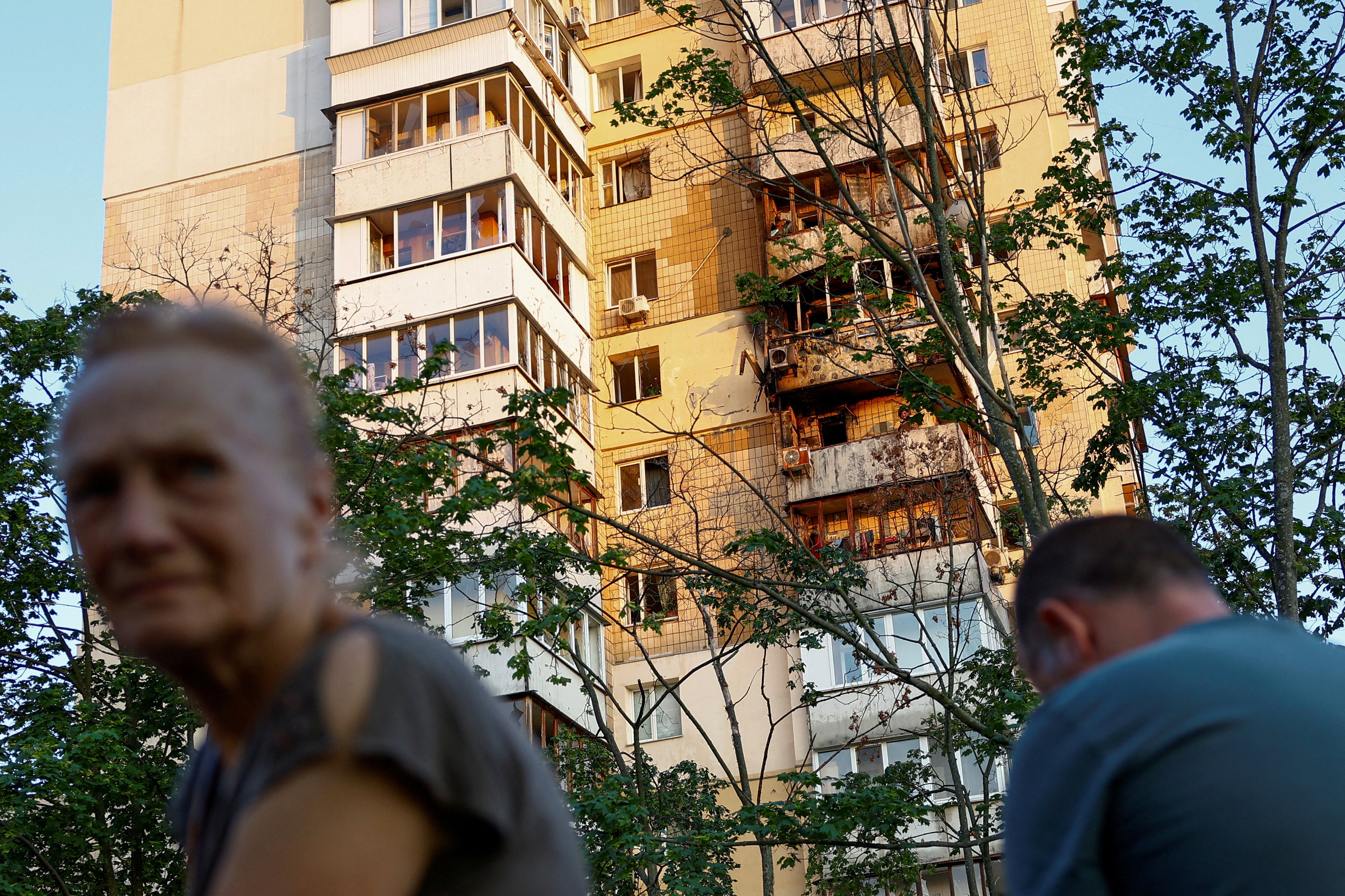 Local residents stand next to an apartment building damaged during a Russian missile strike, amid Russia's attack on Ukraine, in Kyiv, Ukraine