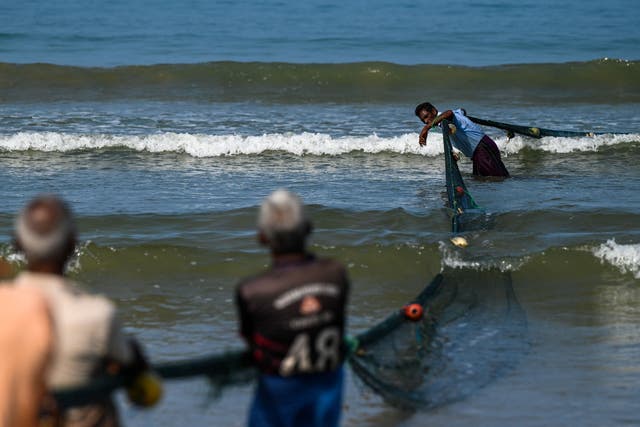 <p>Fishermen pull a fishing net at a beach in Galle, Sri Lanka</p>
