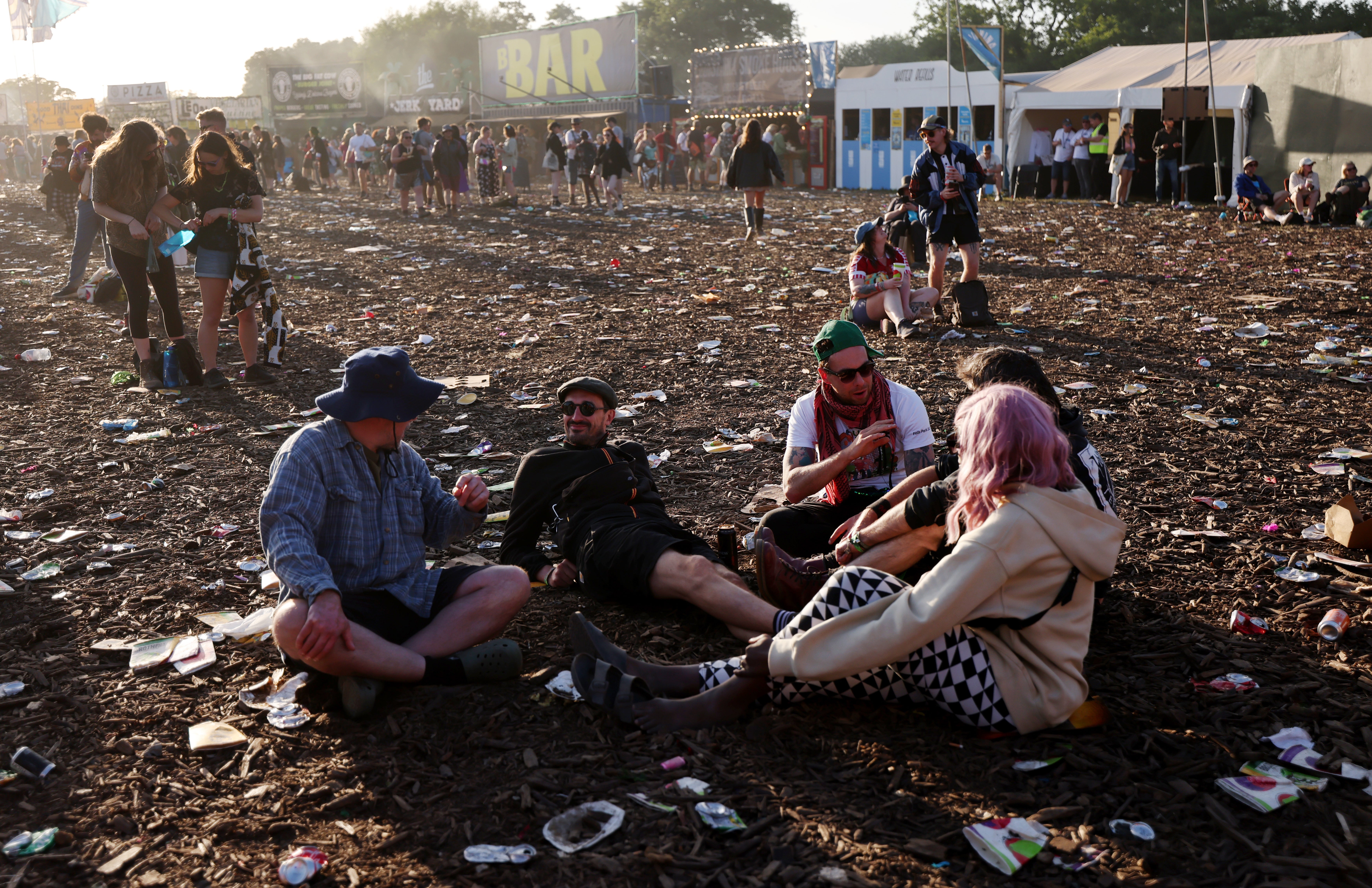 Festival-goers sit amongst rubbish on the third day of the festival