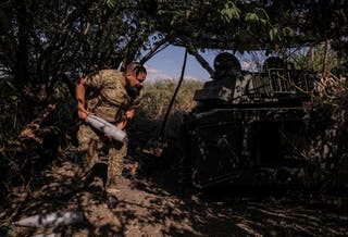 A serviceman of 24th Mechanized Brigade of the Ukrainian Armed Forces, named after King Danylo, loads a shell inside a 2S1 Gvozdika self-propelled howitzer during fire towards Russian troops on a front line