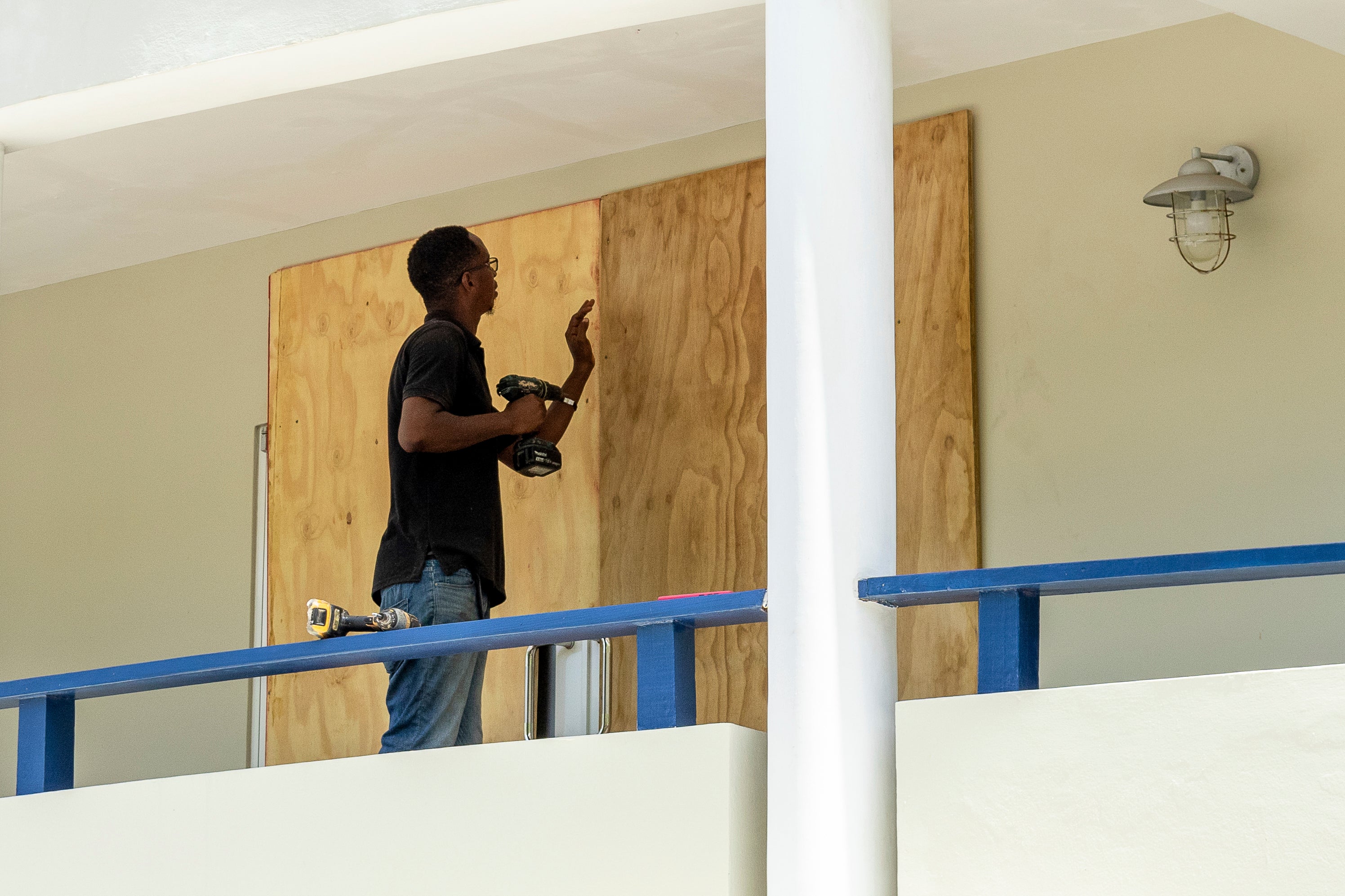 A man drills wood onto a door as Hurricane Beryl approaches in Calliaqua, St Vincent and the Grenadines on Sunday