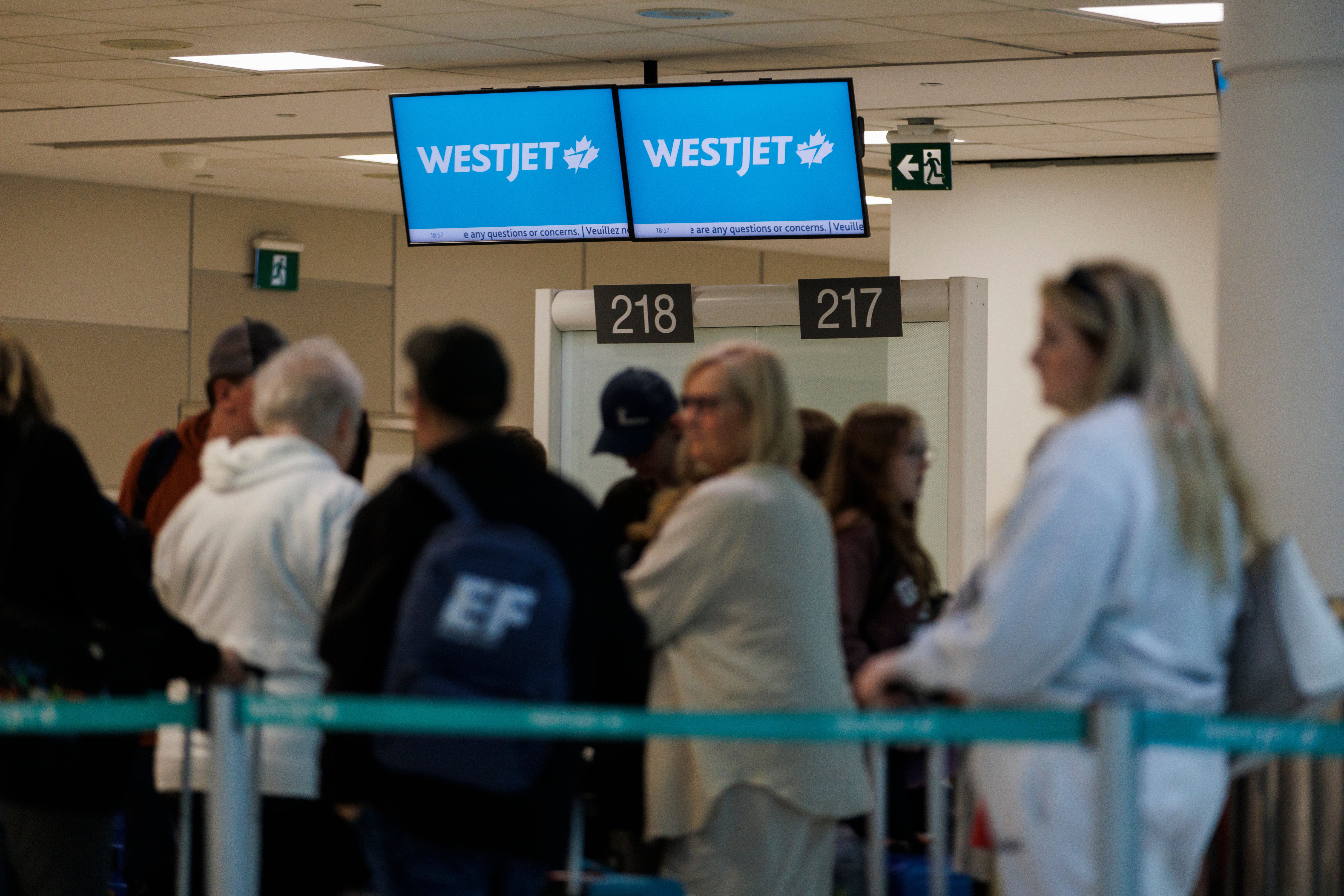 Travellers wait in a queue at a Westjet counter in Toronto Pearson International airport on Sunday after hundreds of flights were cancelled due to strike action
