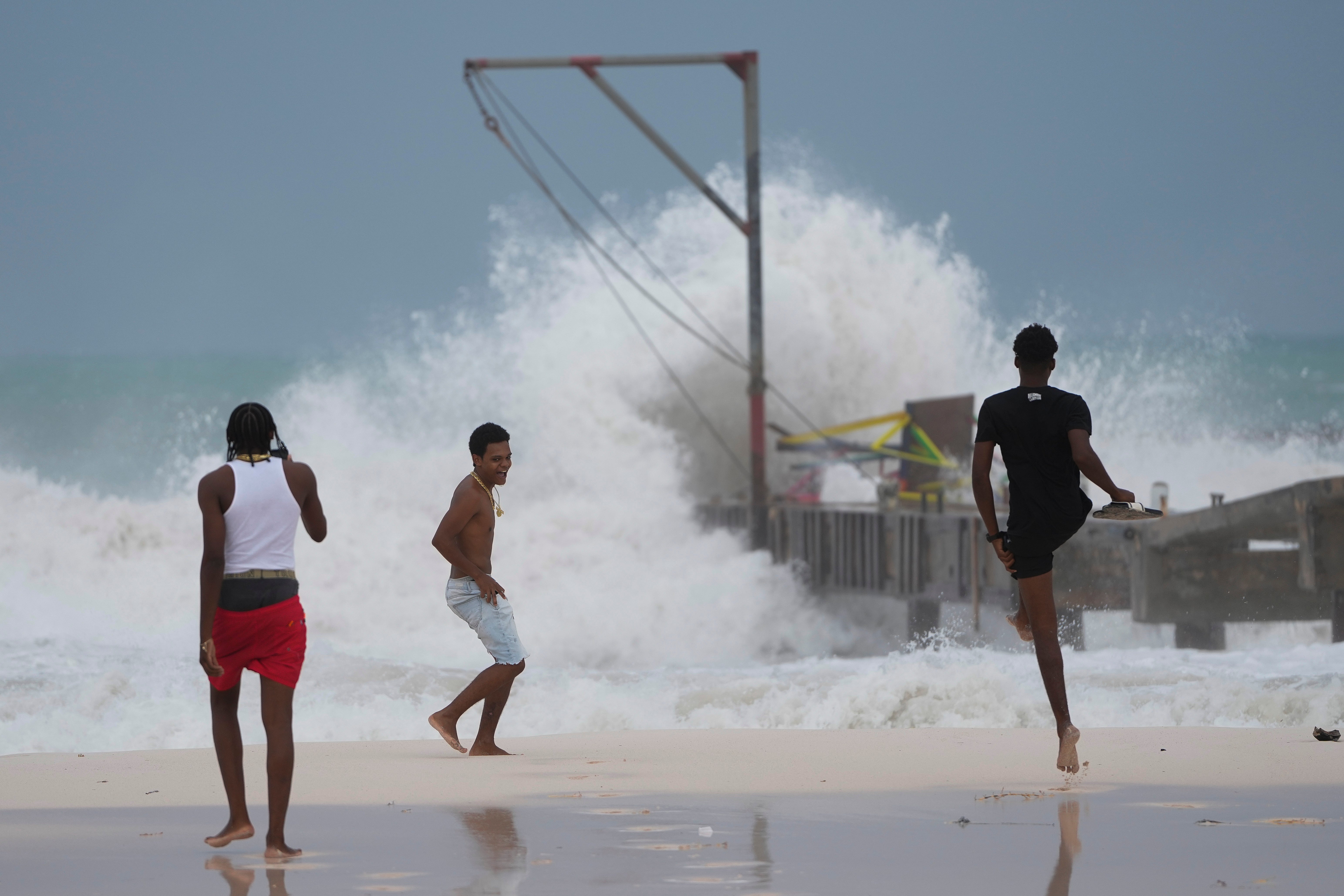 Three people watch as Hurricane Beryl brings destructive winds and storm surge to Bridgetown, Barbados on Monday