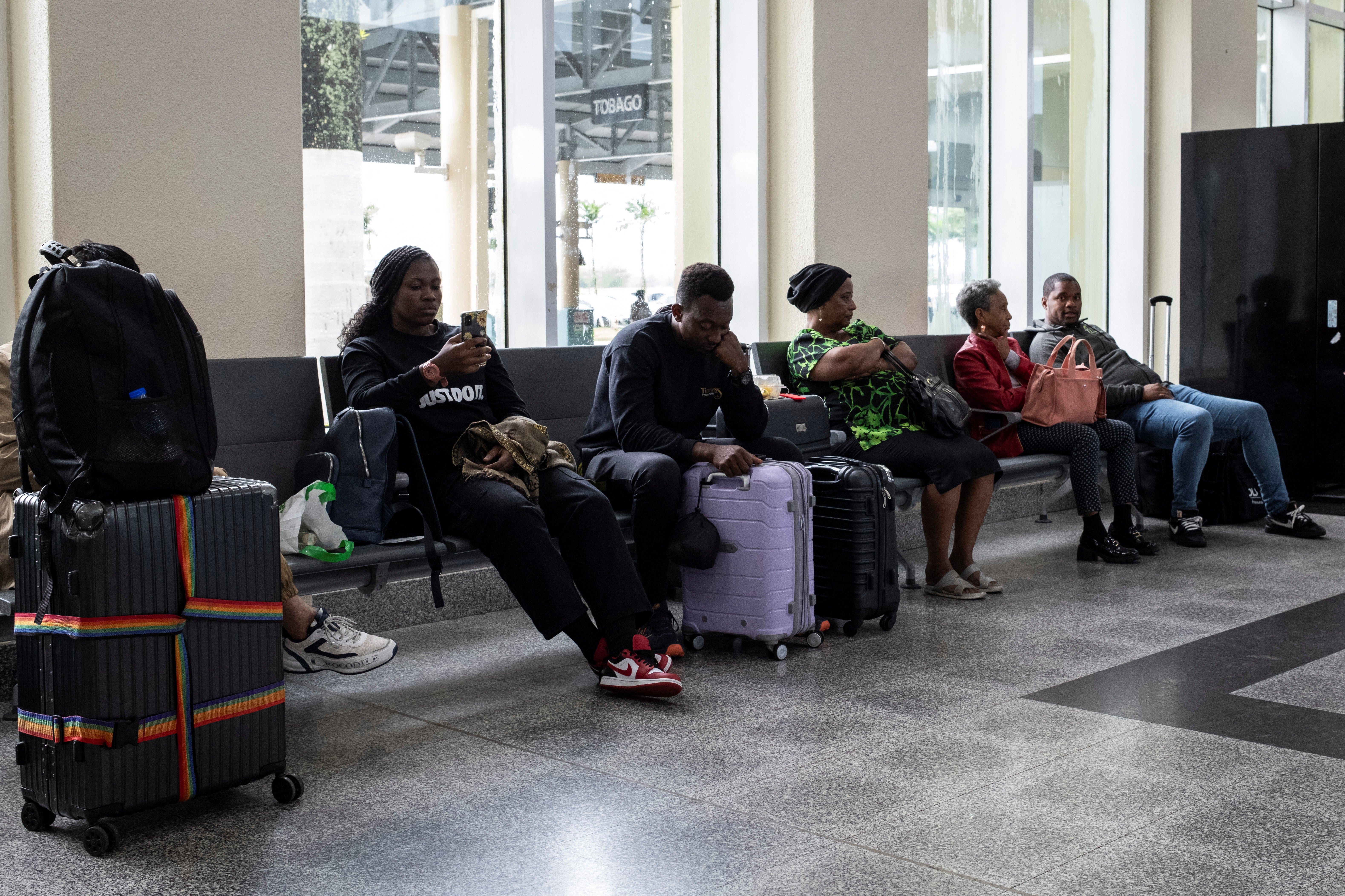 Travelers wait at Piarco International Airport as flights were delayed and canceled due to Hurricane Beryl.