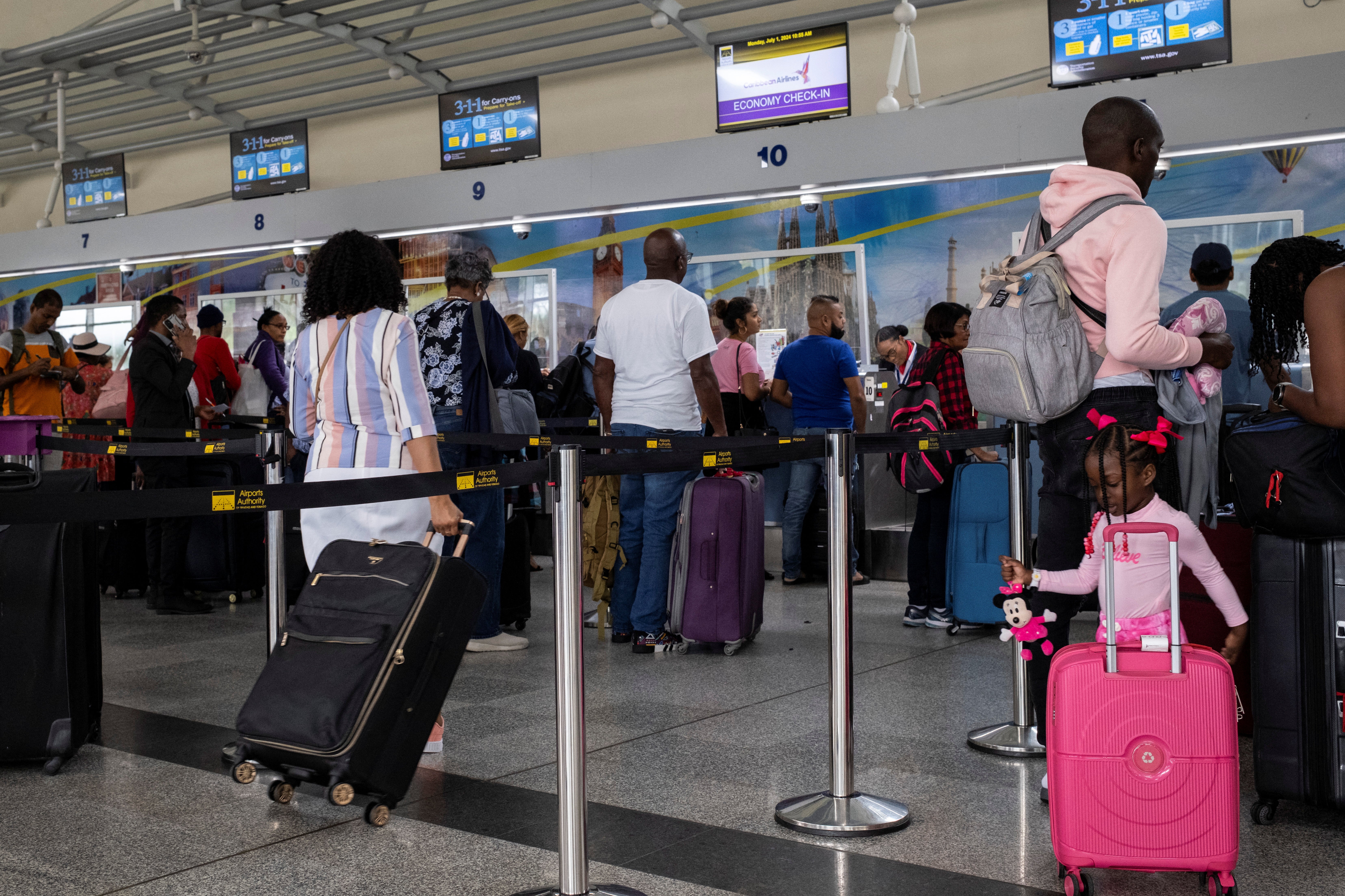 يصطف الناس عند المنضدة في مطار بياركو الدولي حيث تم إلغاء الرحلات الجوية بسبب إعصار بيريل