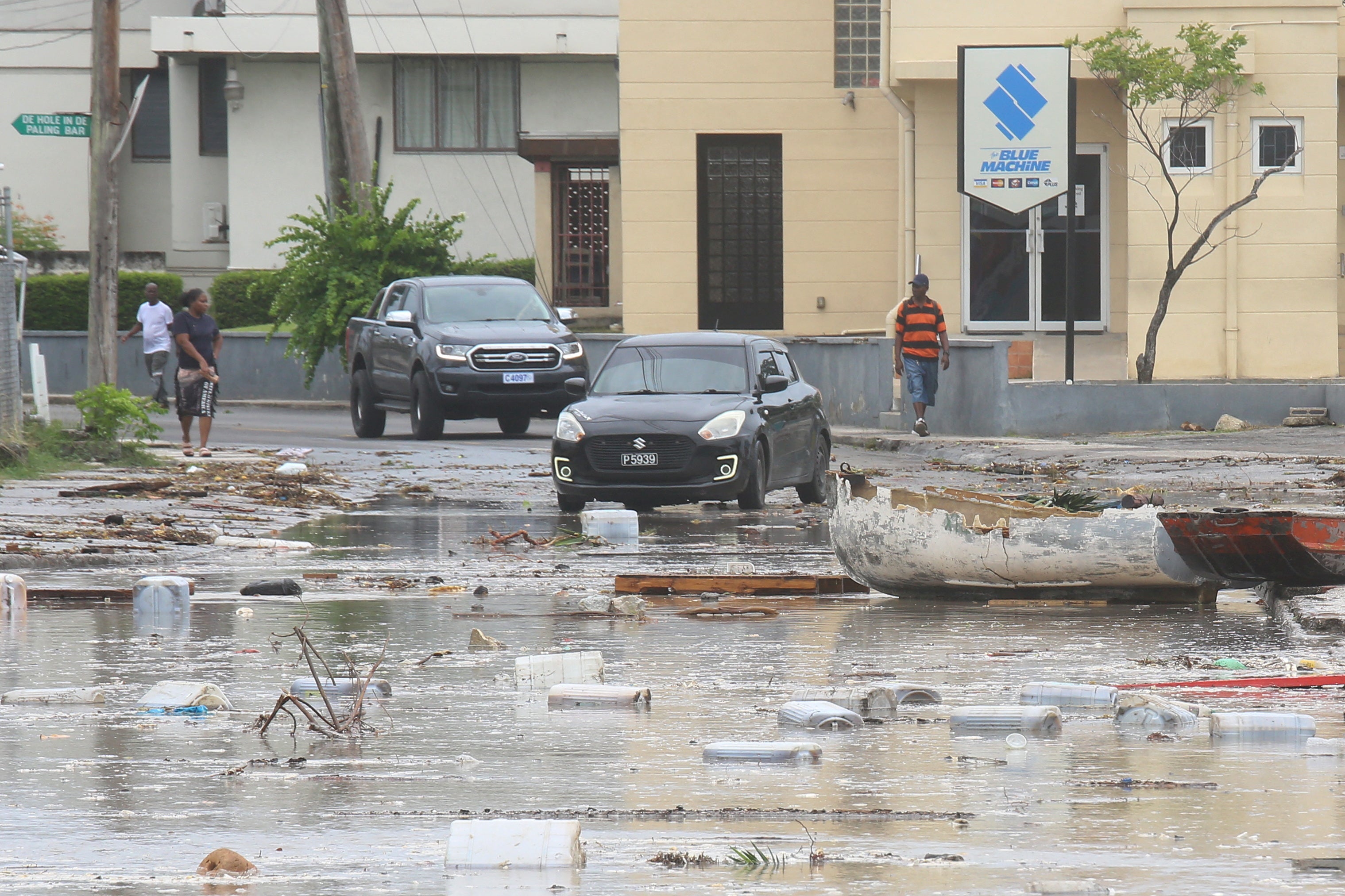 ハリケーンベリルが島を襲った後、バルバドスブリッジタウンの残骸がいっぱいの街を車が走っている