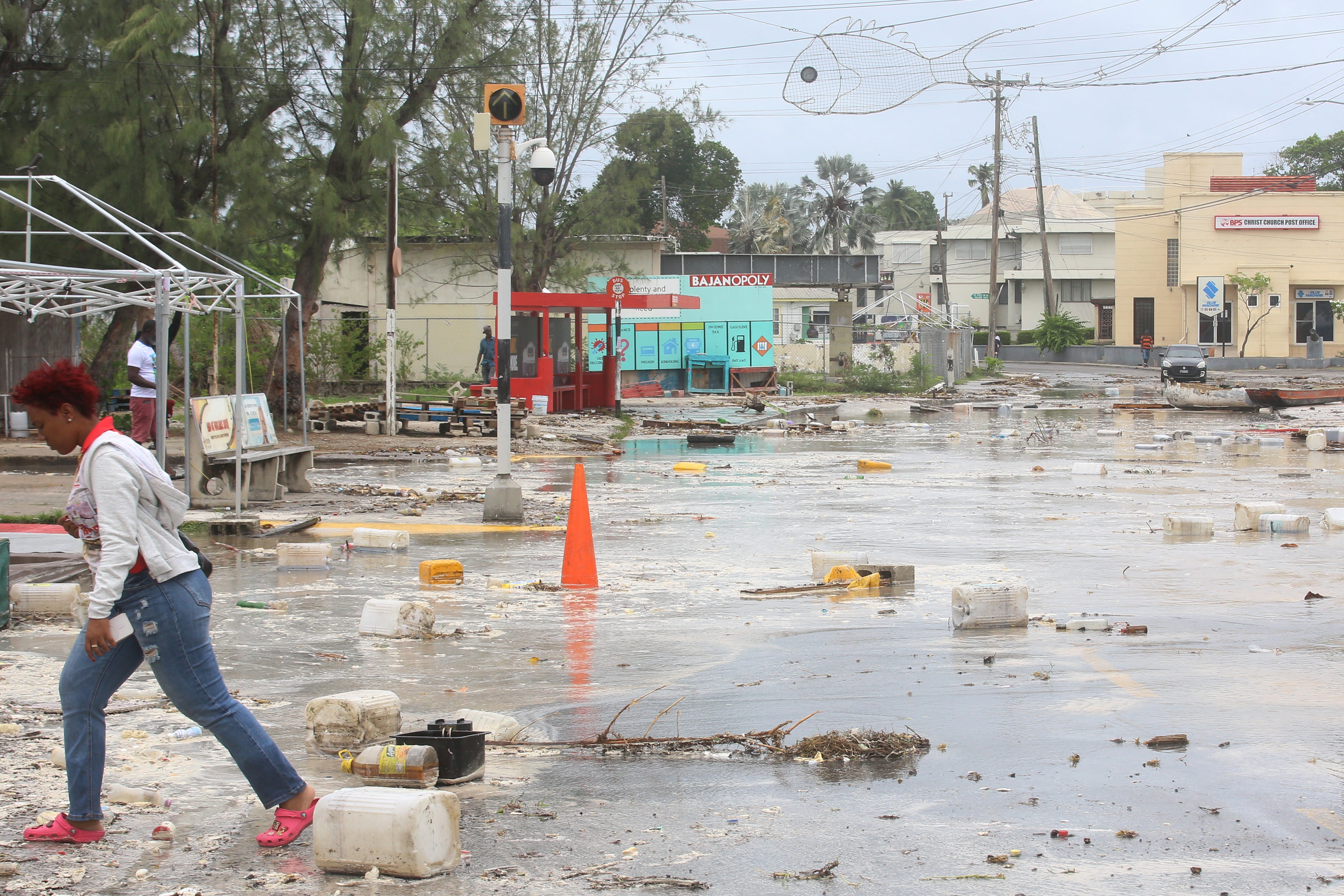 امرأة تمشي في شارع مليء بالحطام في بريدج تاون، بربادوس، بعد أن ضرب الإعصار بيريل الجزيرة