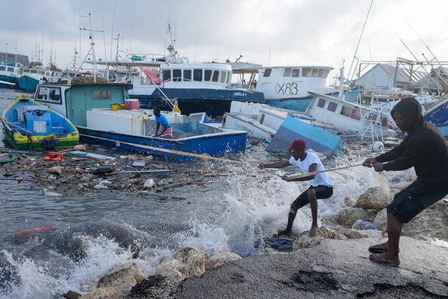 <p>Fishermen pull a boat damaged by Hurricane Beryl back to the dock at the Bridgetown Fisheries in Barbados</p>