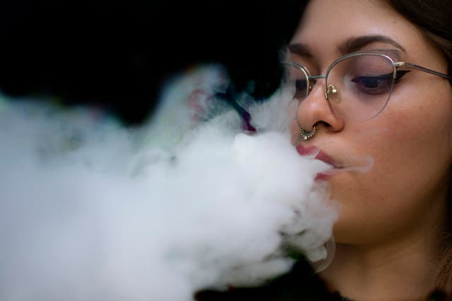 <p>A woman blows smoke from an electronic cigarette</p>