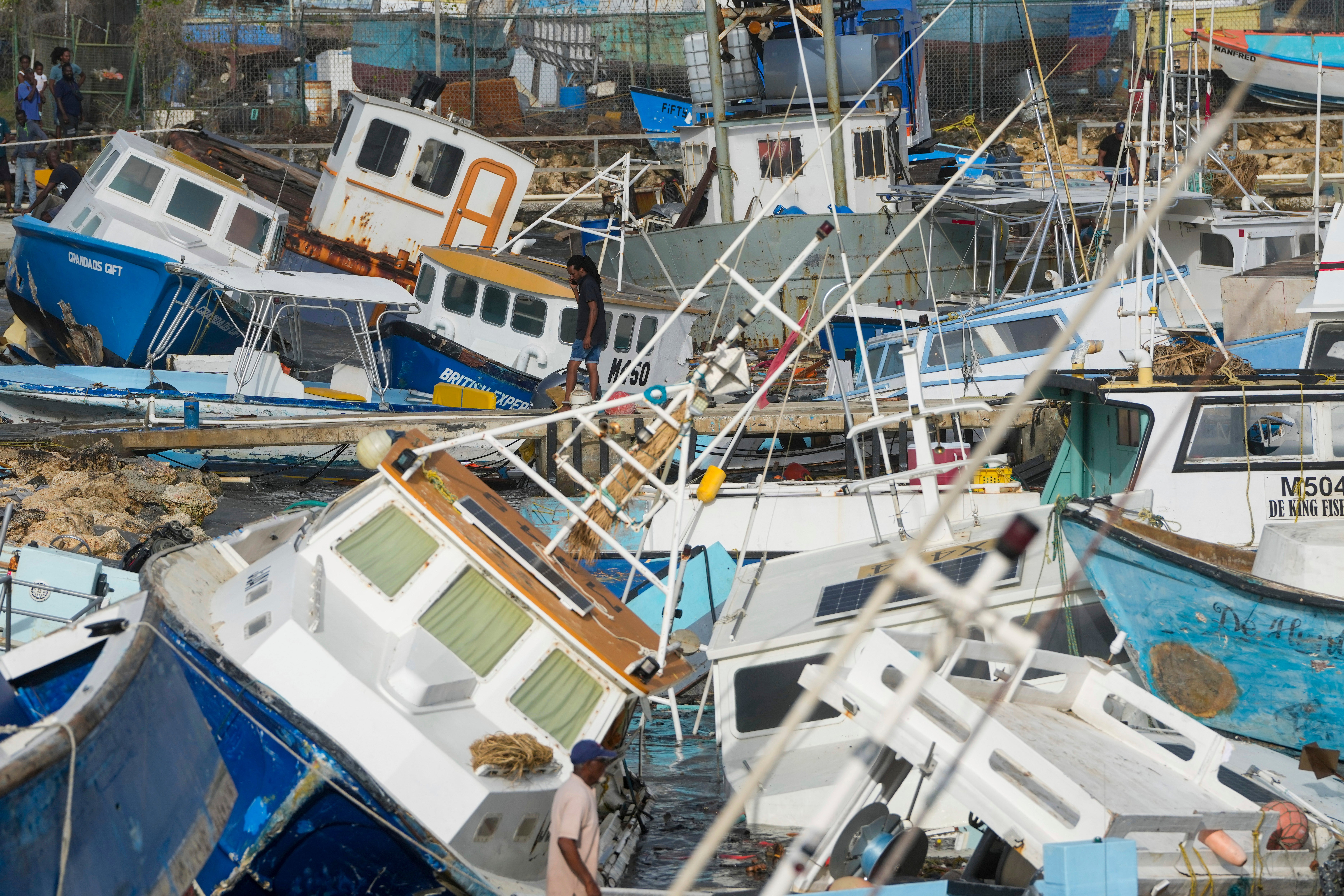 A man looks at damaged fishing boats after Hurricane Beryl blew through Barbados