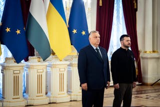 Премьер-министр Венгрии Виктор Орбан стоит с президентом Украины Владимиром Зеленским перед флагами ЕС, Венгрии и Украины.