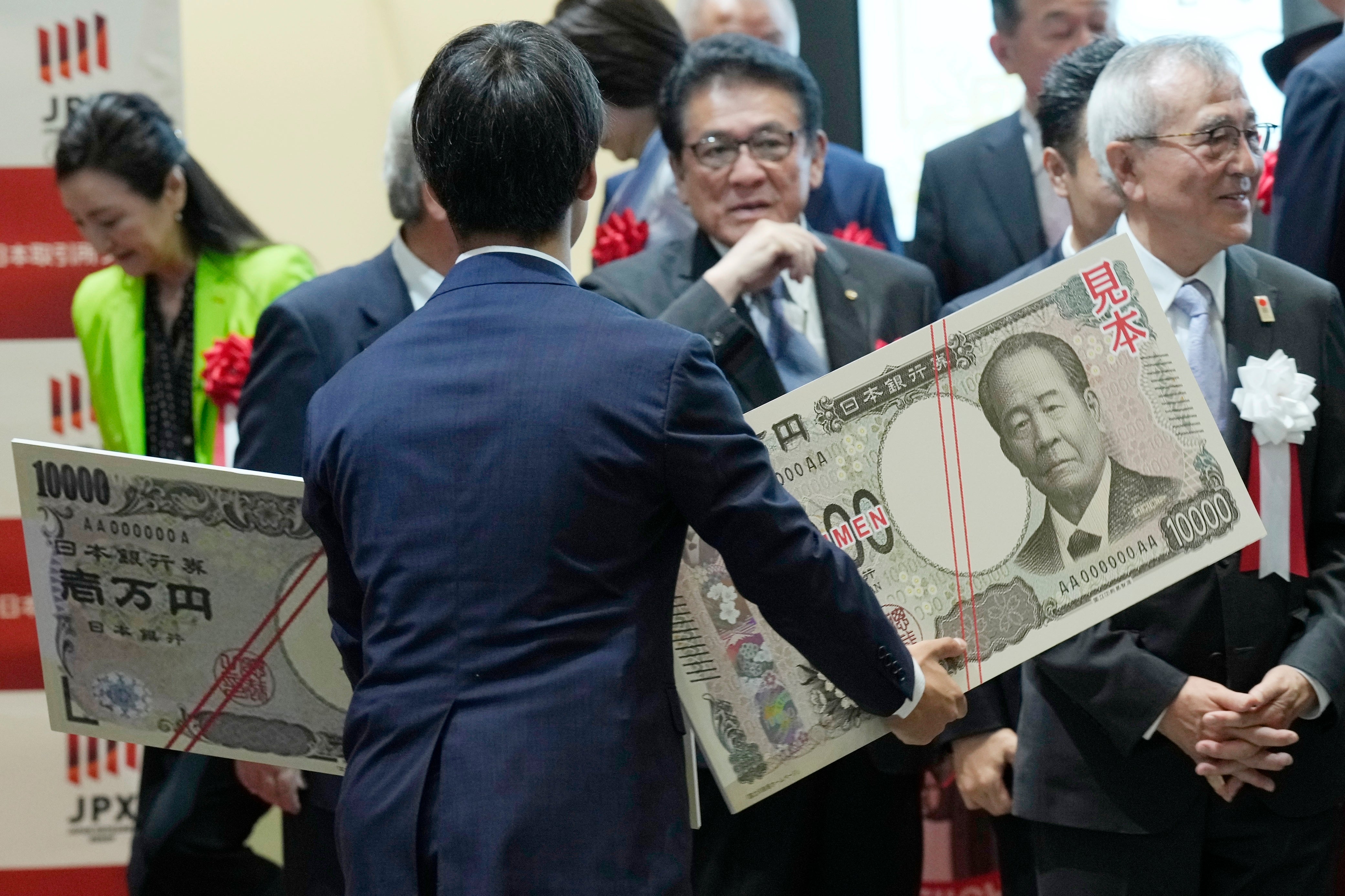 <p>A staffer holds enlarged copies of old and new 10,000 yen notes at Tokyo Stock Exchange on 3 July 2024</p>