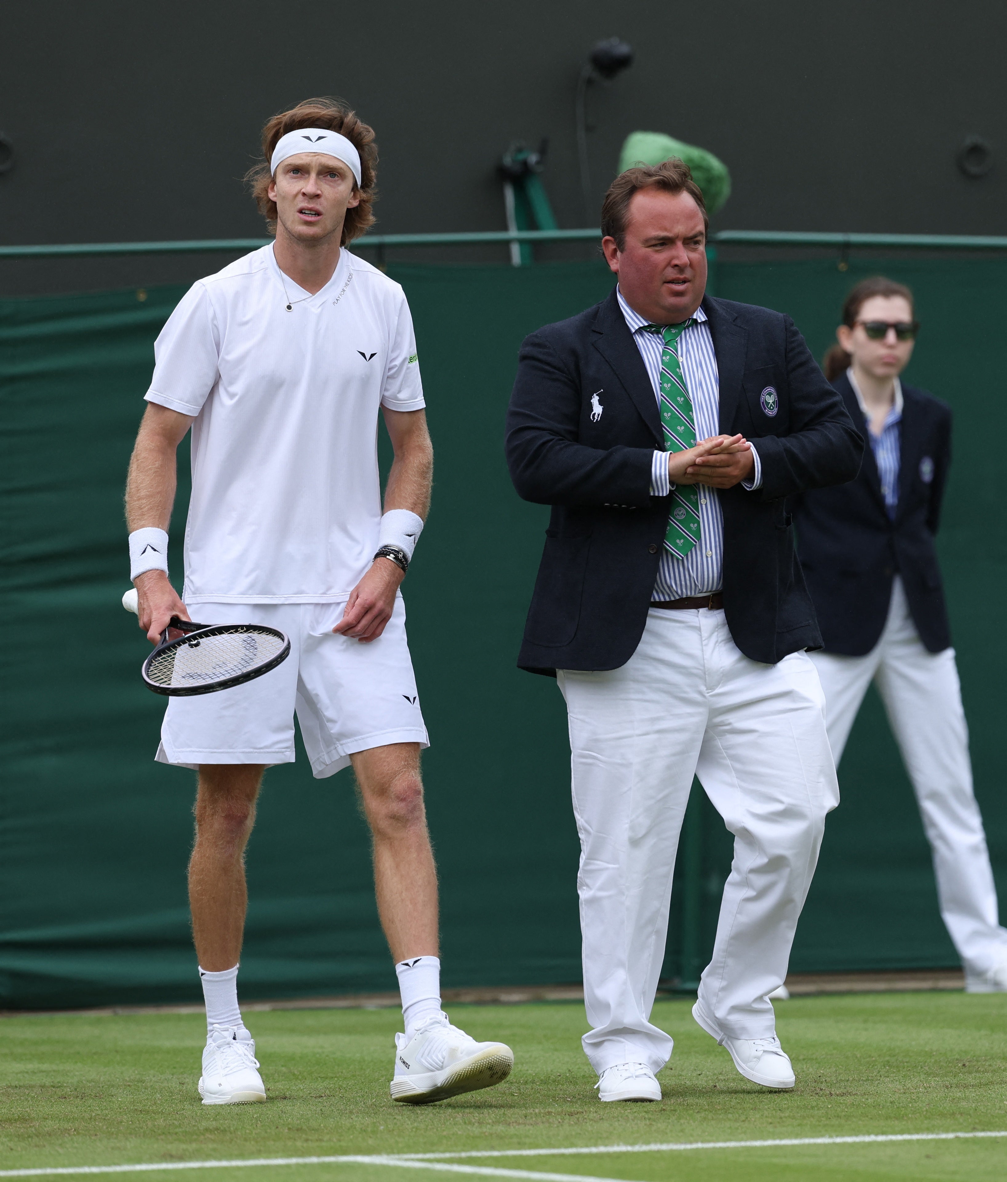 Russia's Andrey Rublev inspects the grass with umpire during his first round