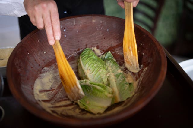 <p>Salad Master Efrain Montoya mixes Romaine leaves with other ingredients as he prepares a Caesar salad at Ceasar’s restaunt</p>