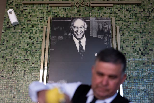 <p>Salad Master Efrain Montoya prepares a Caesar salad in front of an image of the said inventor of the salad, Caesar Cardini</p>