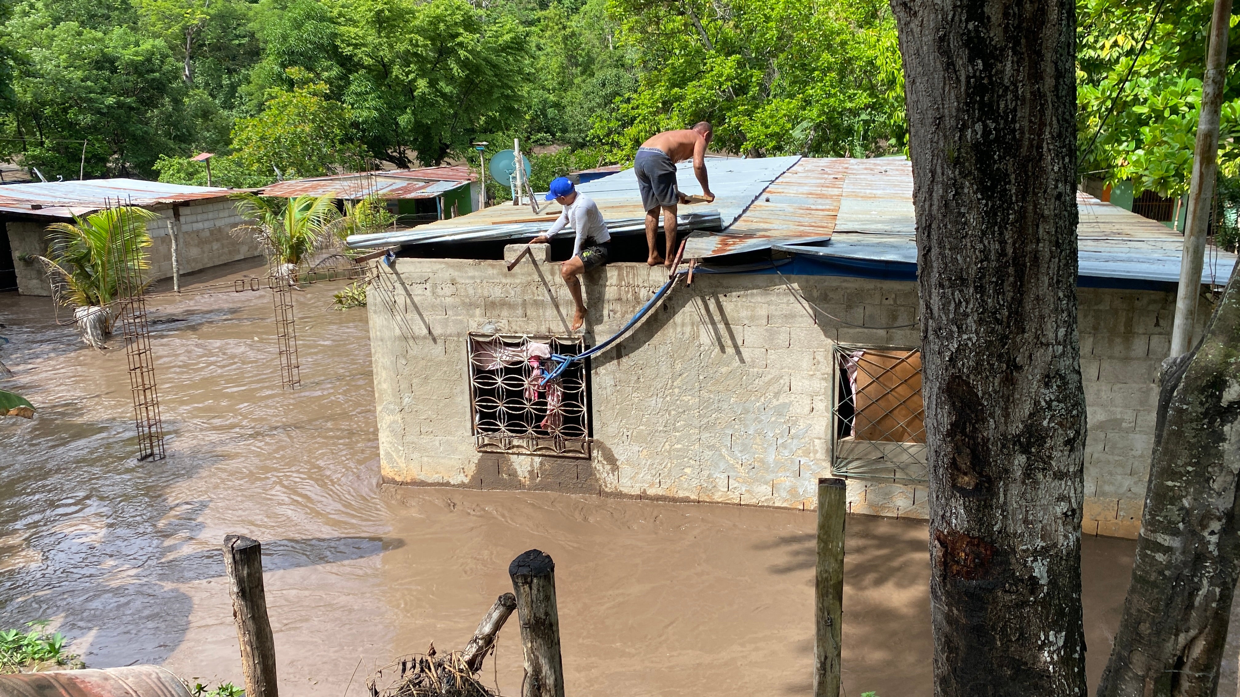 Obyvatelé pracují na opravě střechy zatopené budovy ve Venezuele poté, co oblast zasáhl hurikán Beryl