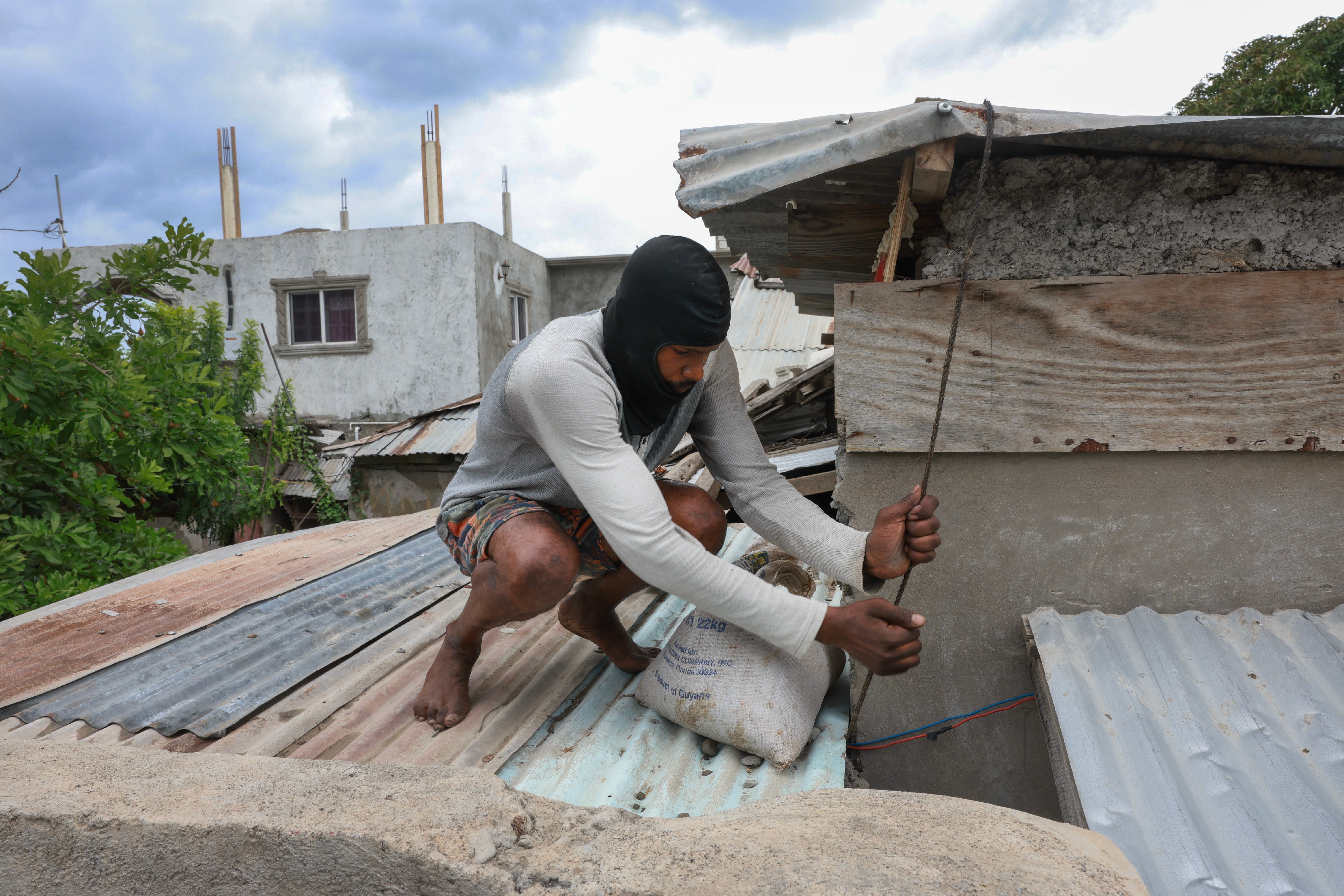 W środę przed huraganem Beryl osoba umieszczała worki z piaskiem na dachu domu w Kingston na Jamajce