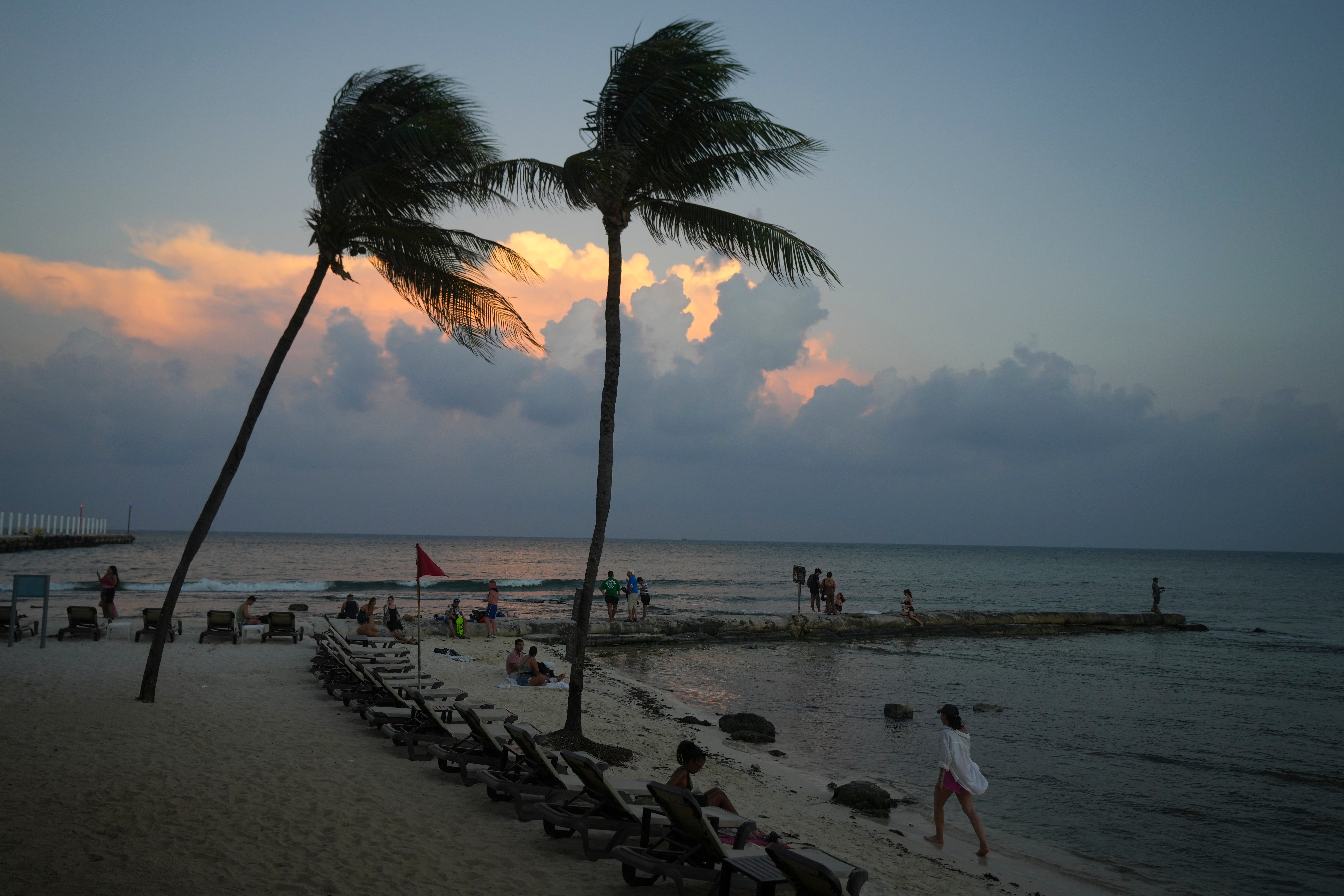 People lounge on the beach as the sun sets ahead of Hurricane Beryl’s expected arrival, in Playa del Carmen, Mexico