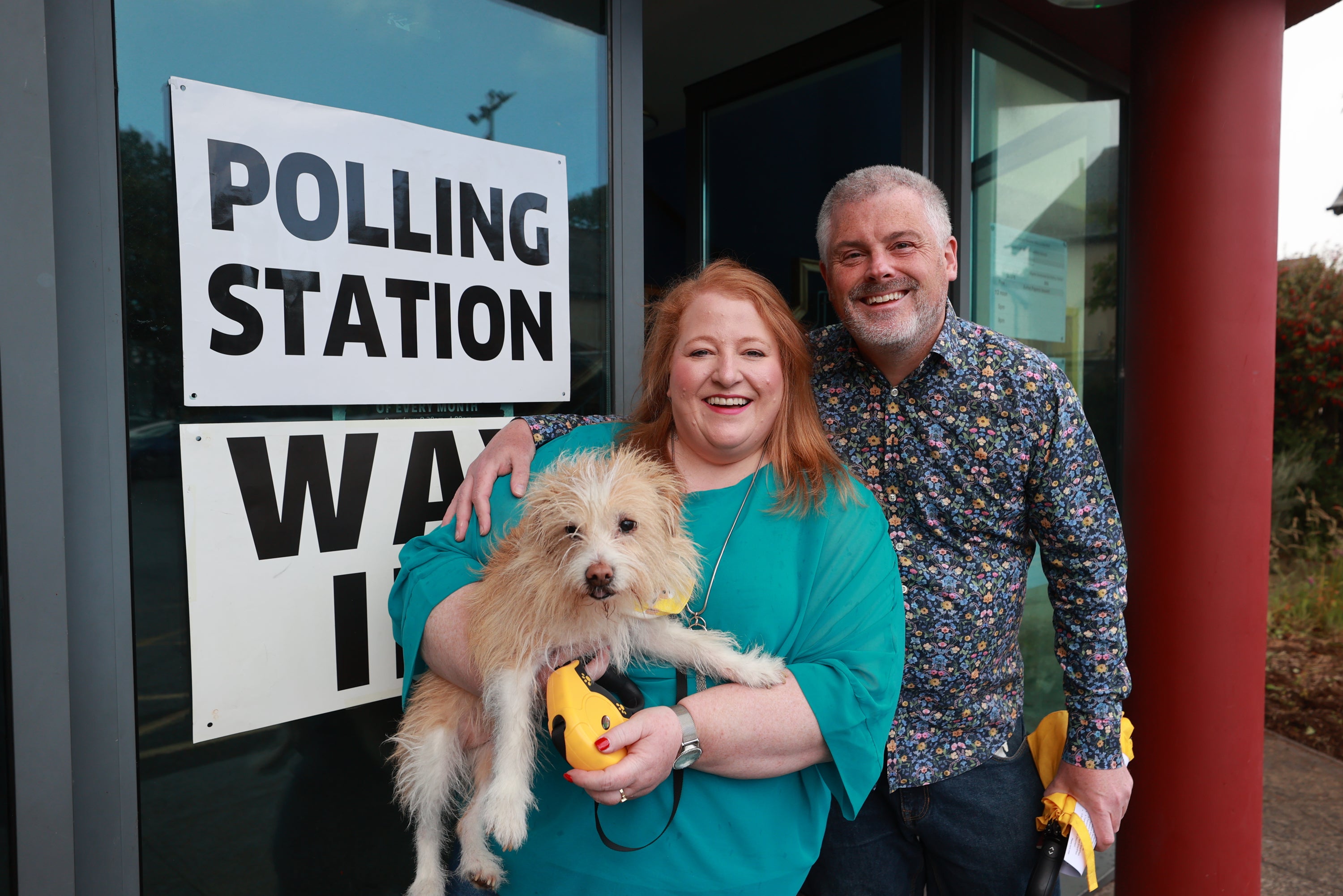 Alliance leader Naomi Long, her husband Michael and their dog Daisy outside the polling station at St Colmcille’s Church (Liam McBurney/PA)