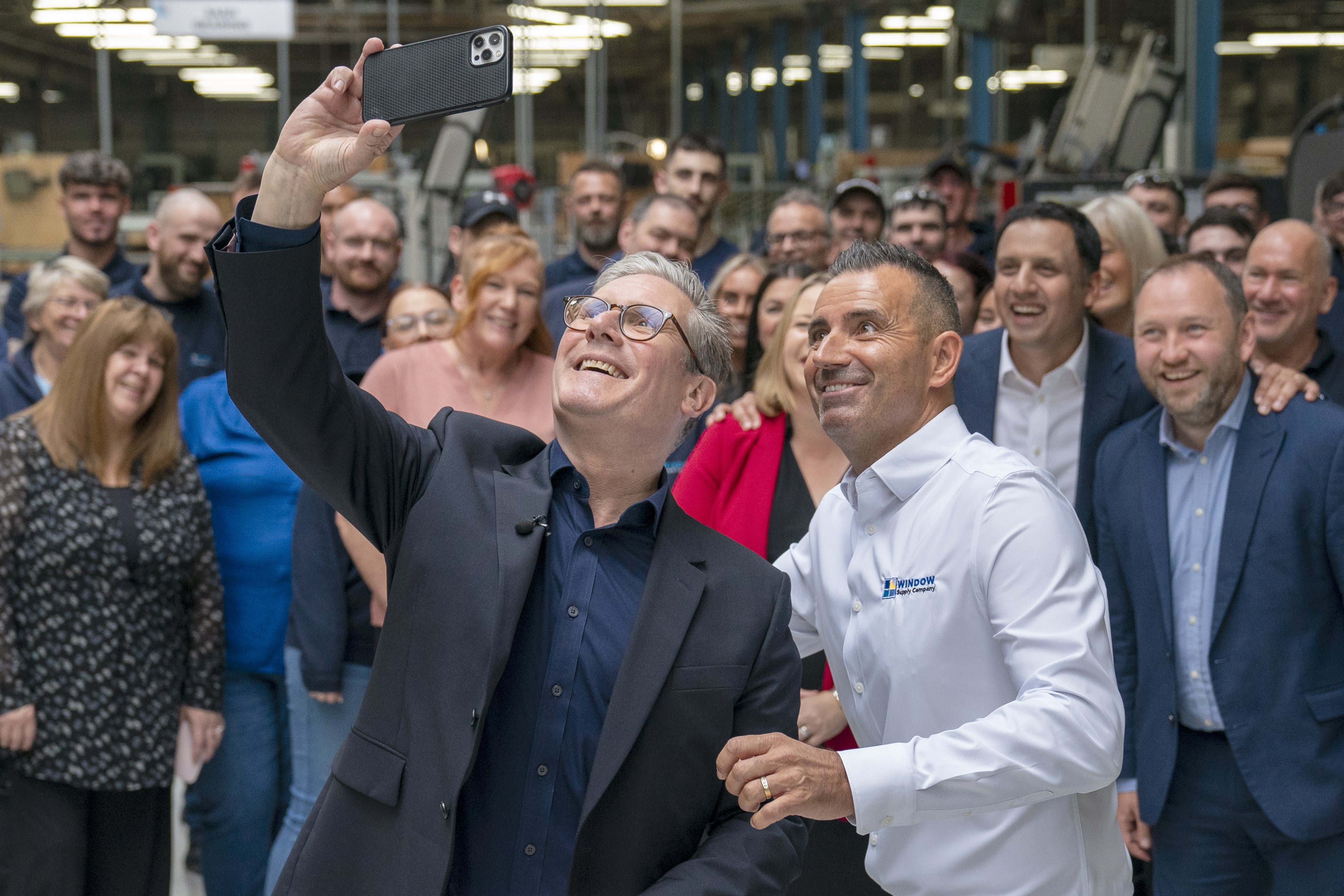 Sir Keir takes a selfie with chief operating officer Martin Linden and staff during a visit to Window Supply Company in Bathgate, West Lothian (Jane Barlow/PA)