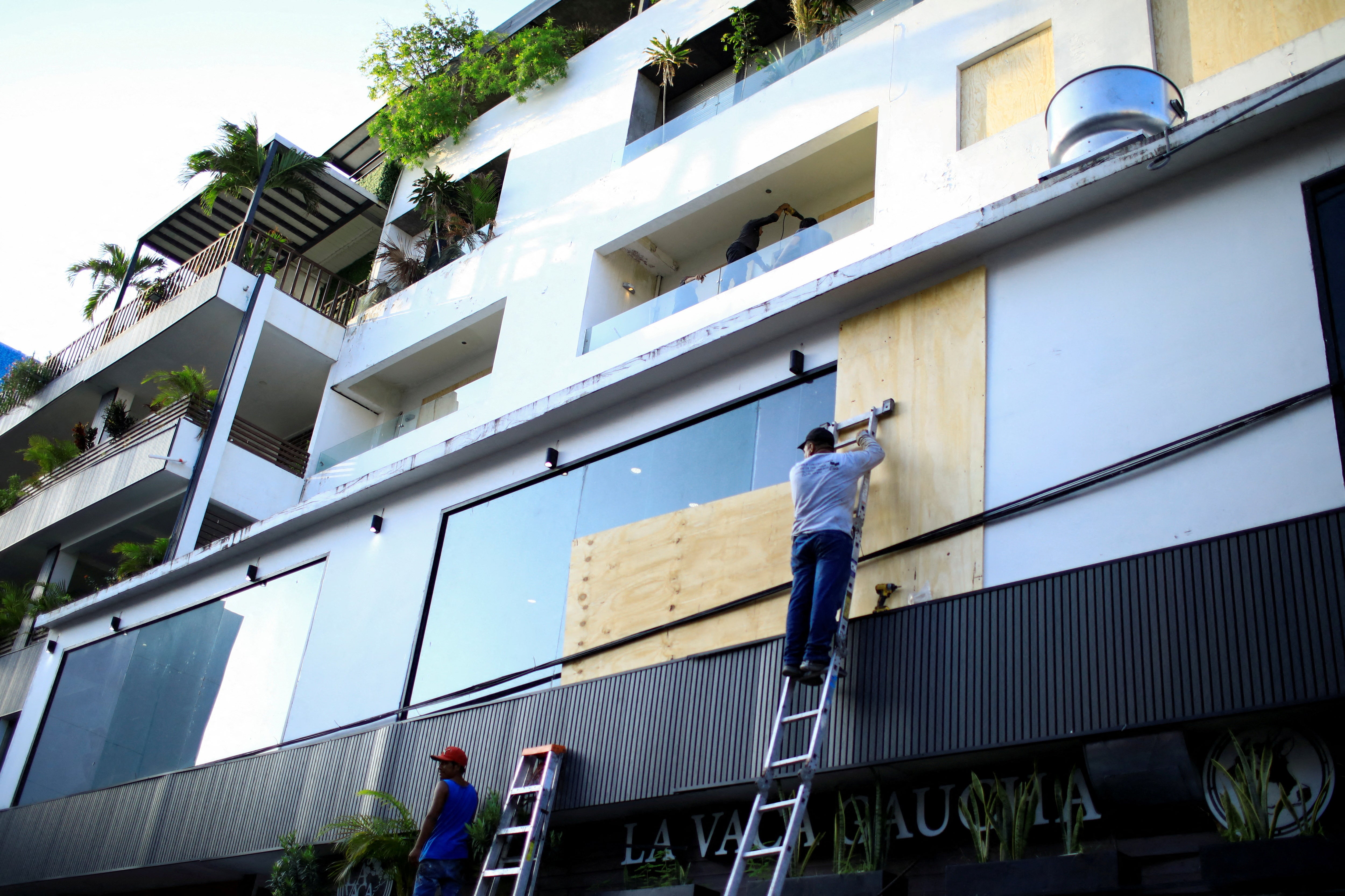 2024年7月3日、メキシコのプラヤ・デル・カルメンで、ハリケーン・ベリルの到来を前に建物の窓に木の板を取り付ける作業員。