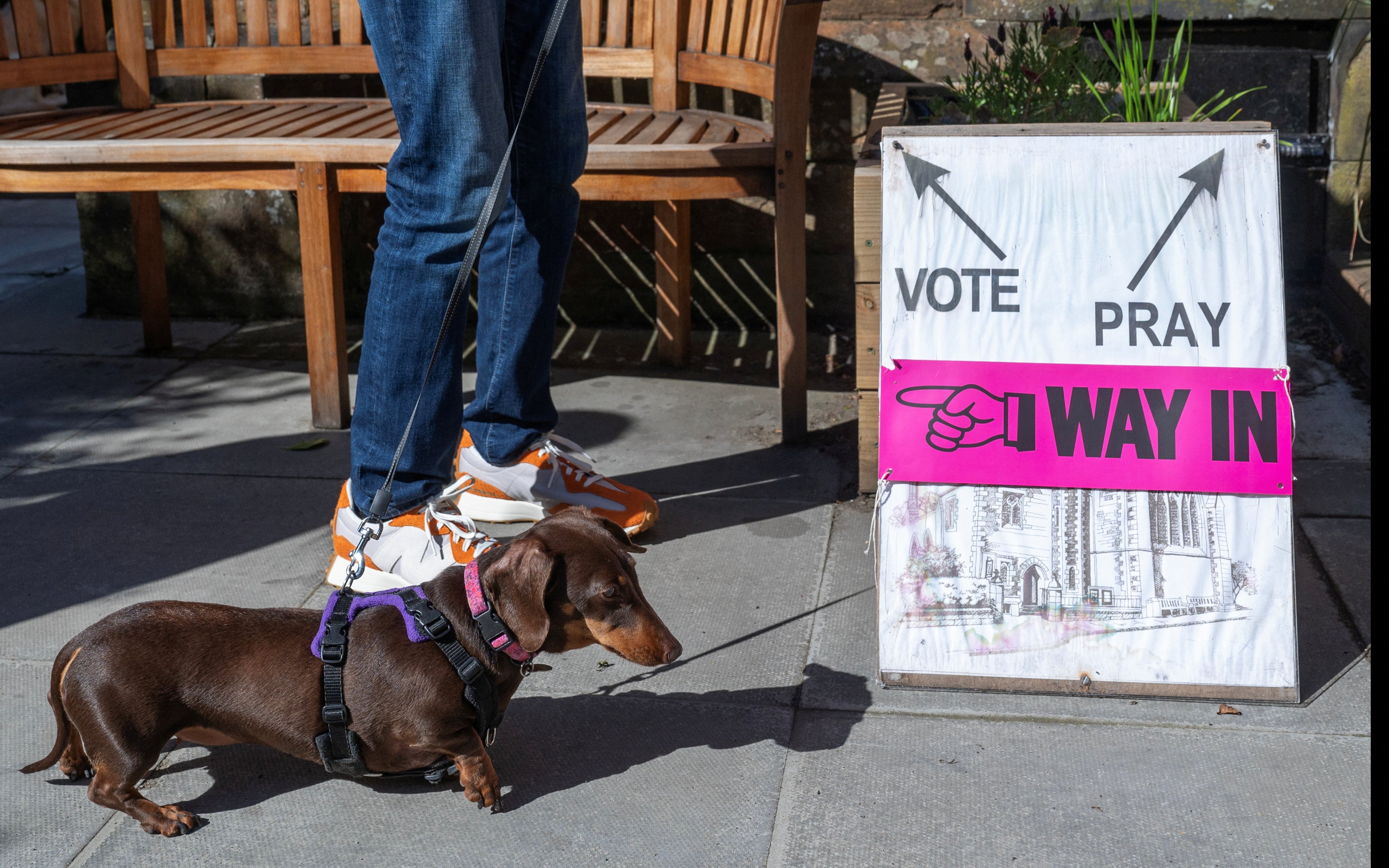 A person and a dog wait outside St James’ Church polling station during the general election in Edinburgh, Scotland