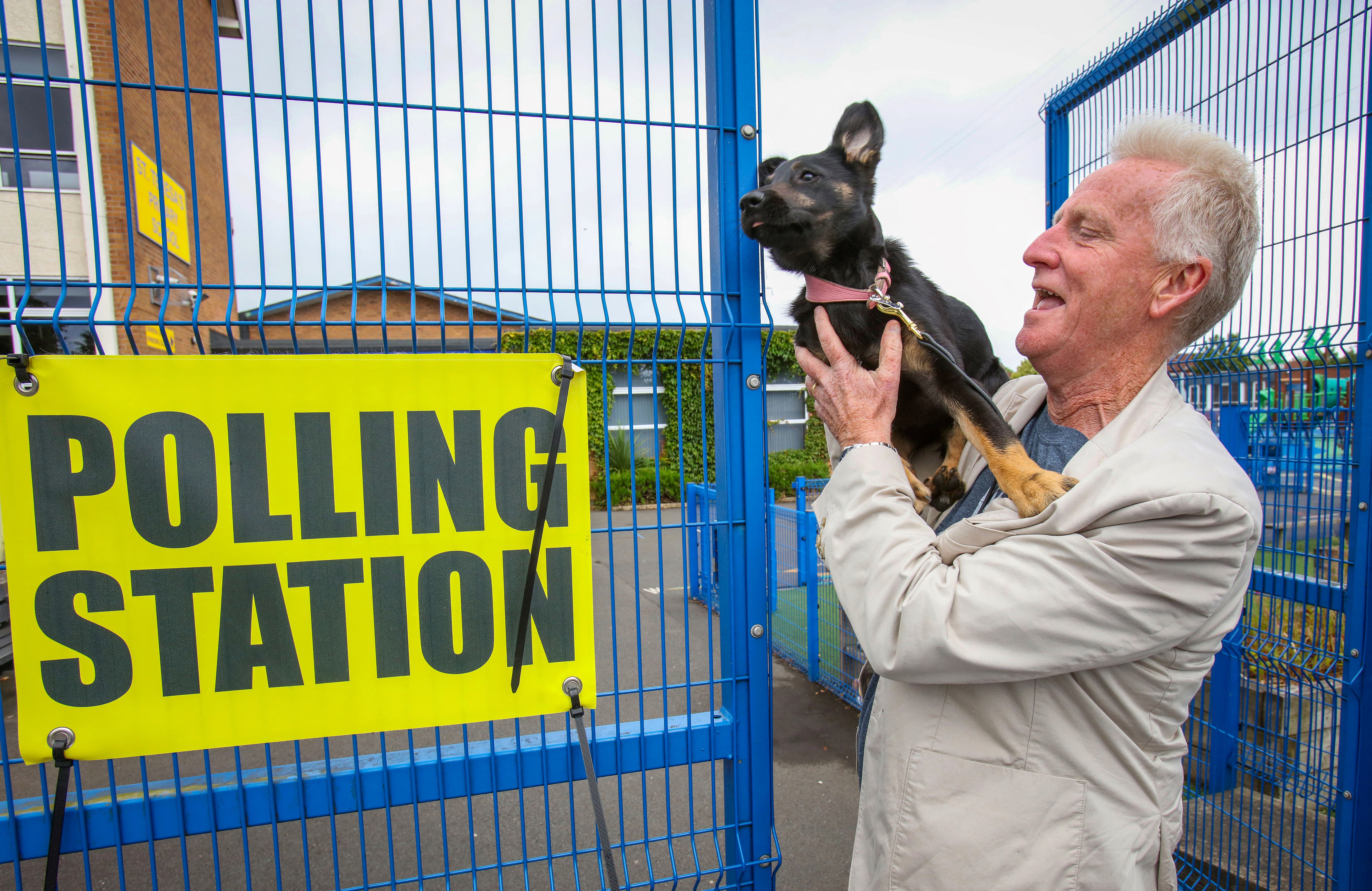 Voter Liam Magee carries his dog Freya outside a polling station in west Belfast