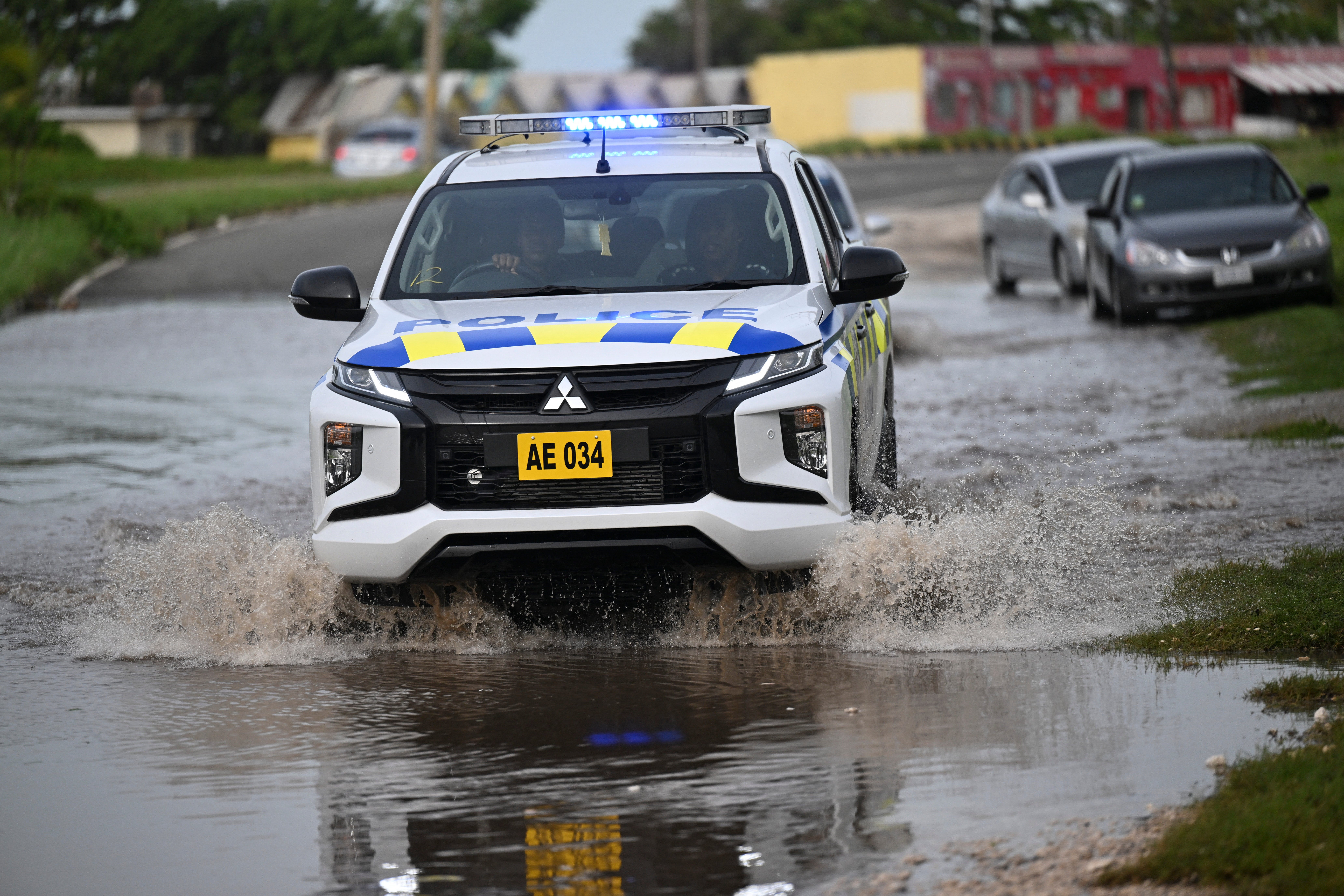 A police car drives through a flooded street in Kingston, Jamaica on Thursday following Hurricane Beryl