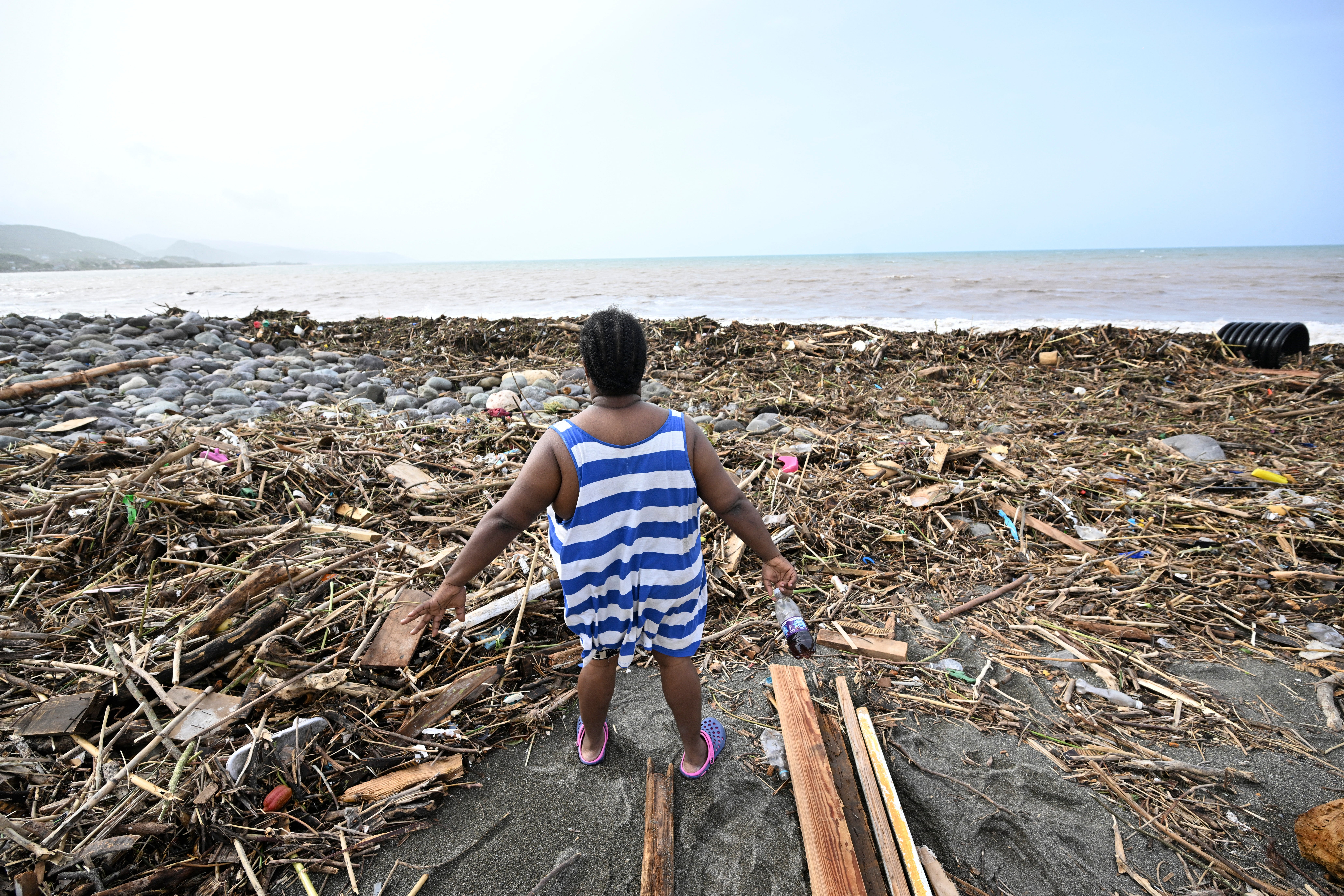 A woman looks at a beach littered with debris in Bull Bay, Jamaica on Thursday after Hurricane Beryl
