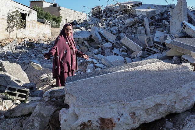 <p>The mother of Ahmed Dawabsha walks on the rubble of her house in the village of Duma in the occupied West Bank</p>